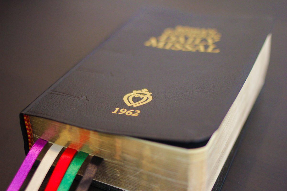 Black leather 1962 Daily Missal with multiple ribbon bookmarks. Gold lettering and emblem on cover.