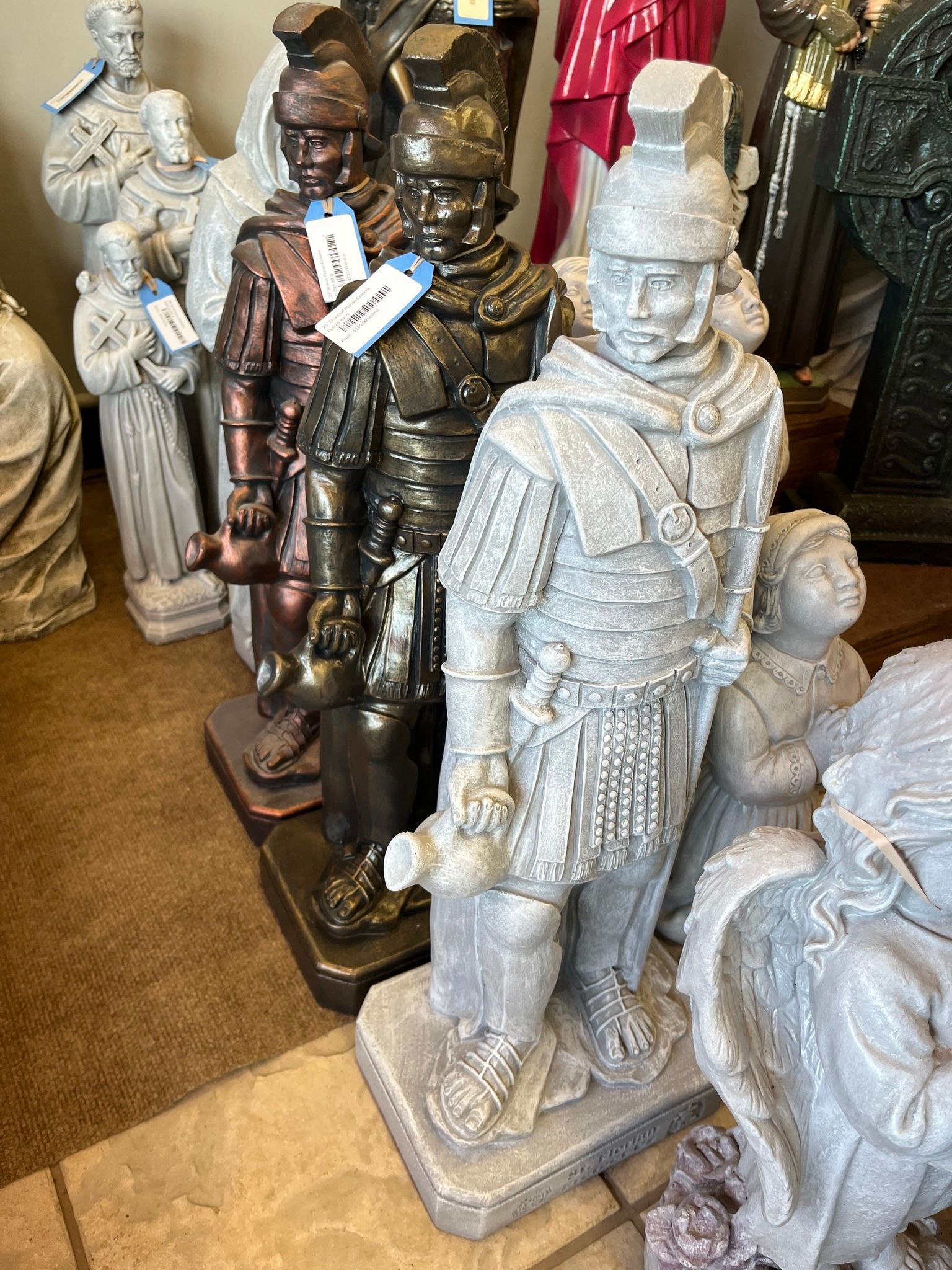 Statues of Roman soldiers, various finishes, standing in a shop.