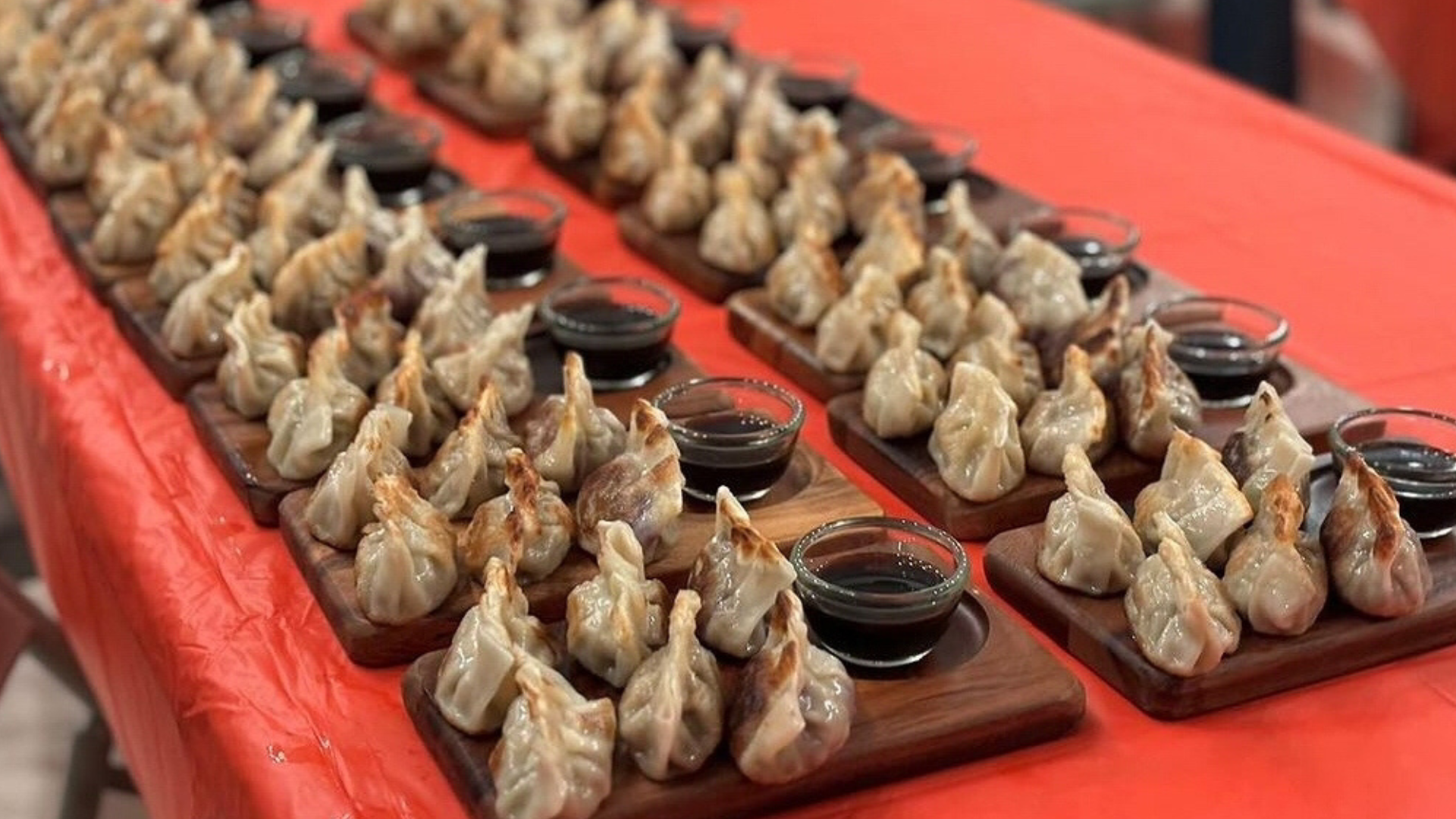 A long row of dumplings sitting on wooden trays on a table