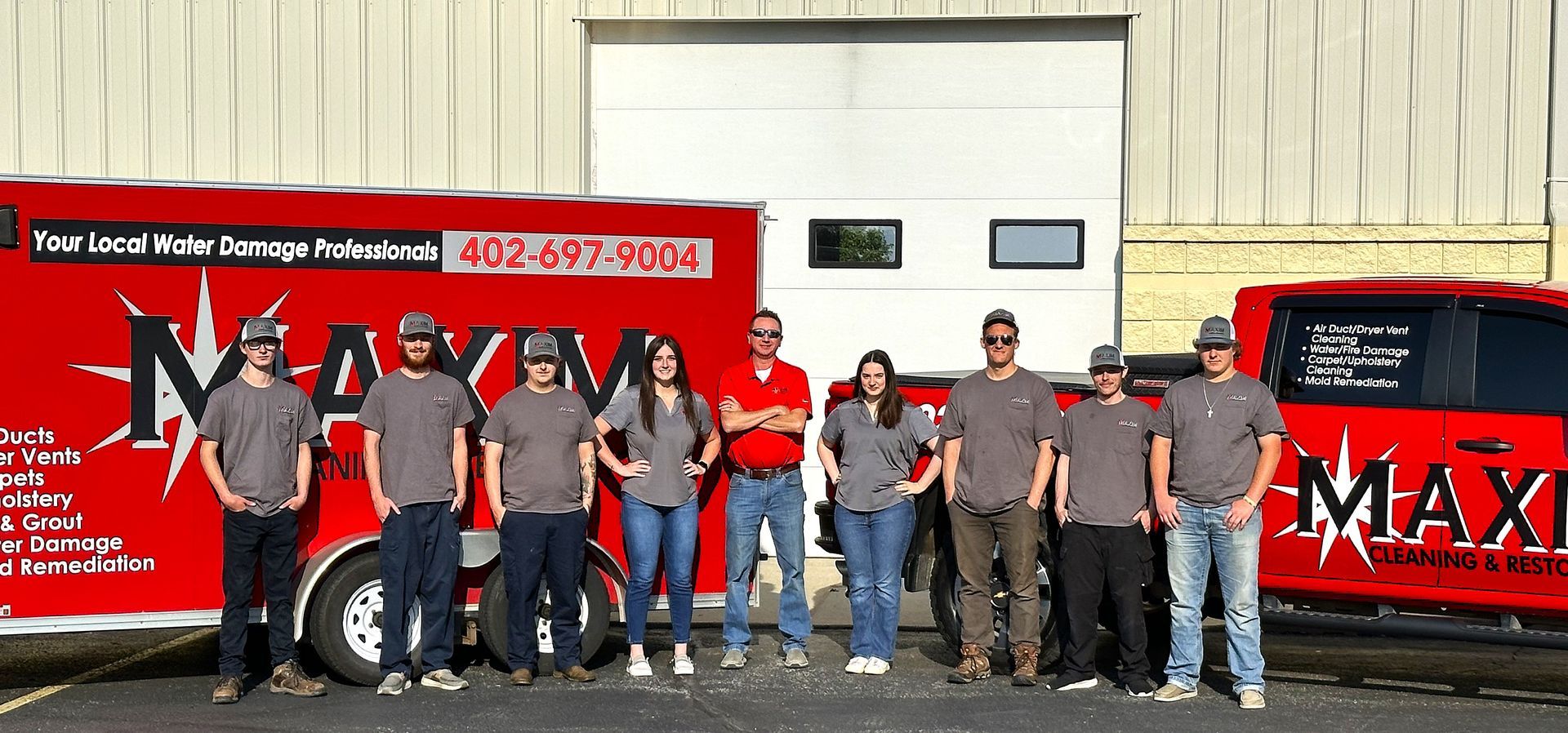 Group of people posing by red vehicles with the 