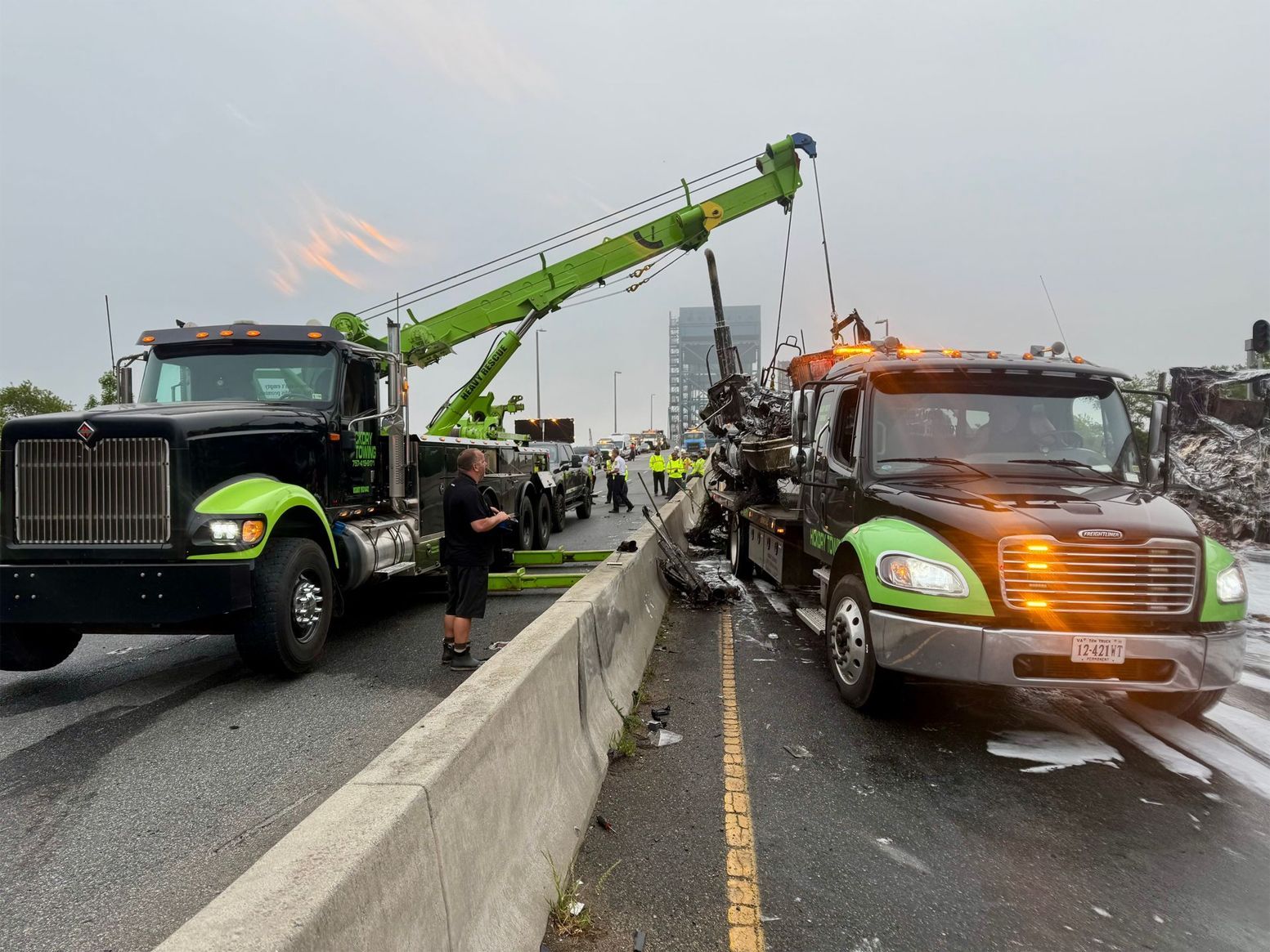 Two tow trucks are parked on the side of a highway.