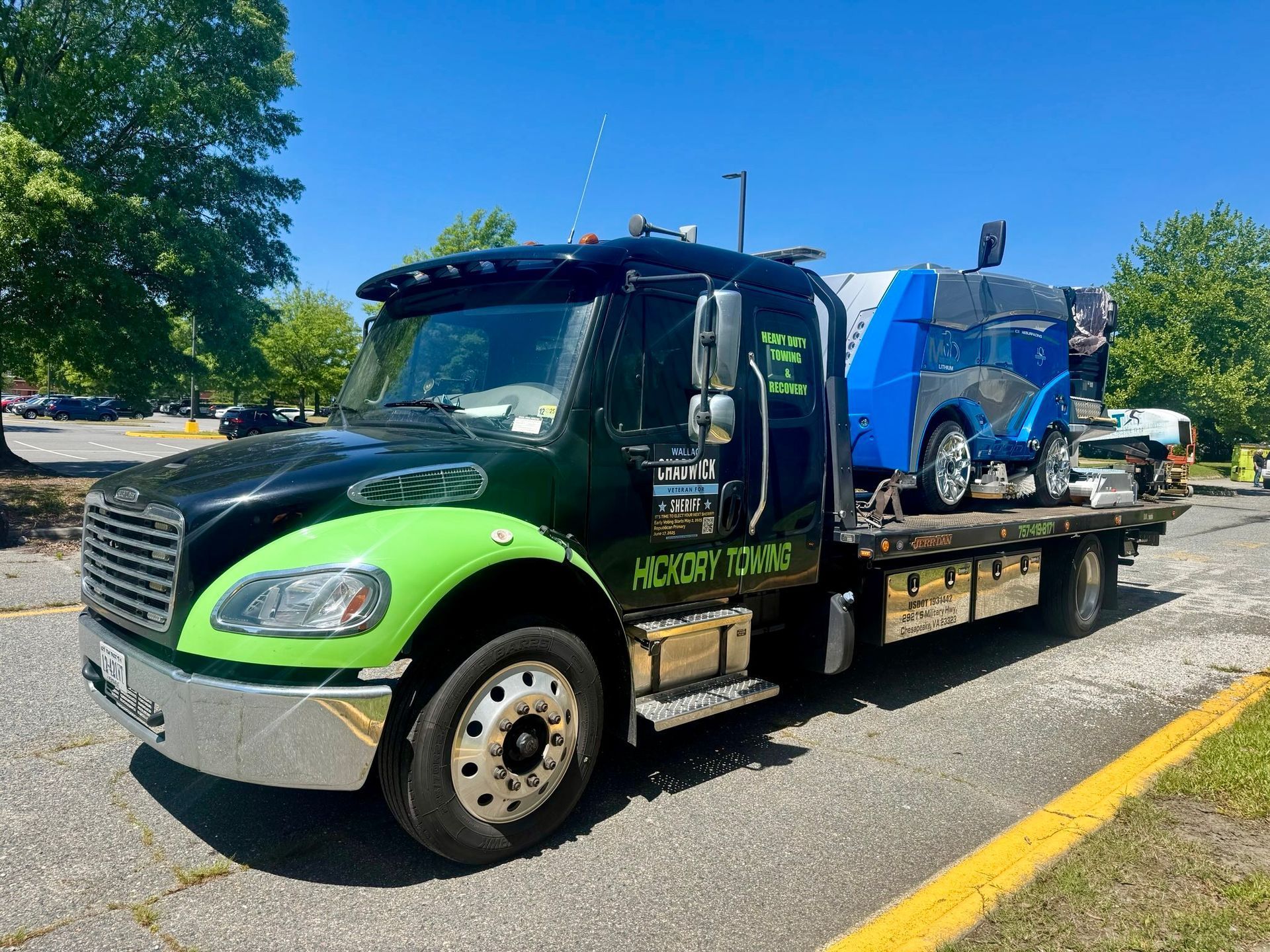 A black and green tow truck is parked in a parking lot.