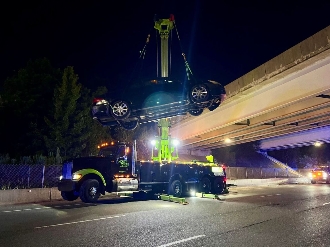 A tow truck is carrying a car over a bridge.