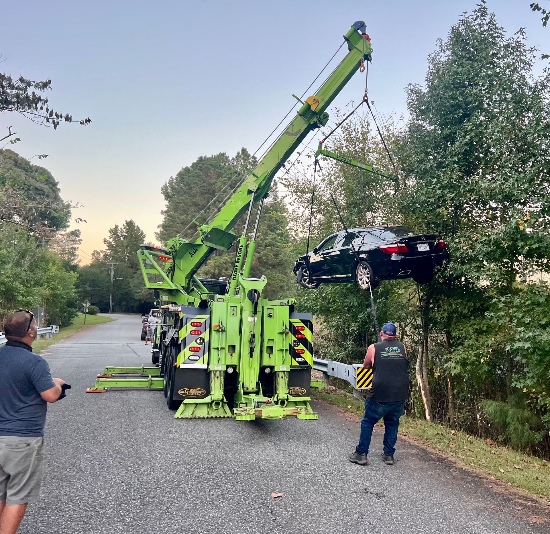 A car is being lifted by a green tow truck.