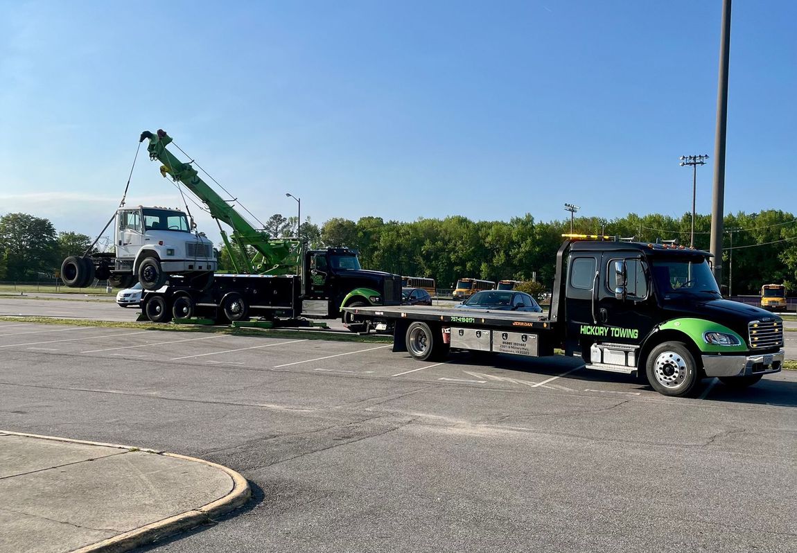 A tow truck is towing a car in a parking lot.