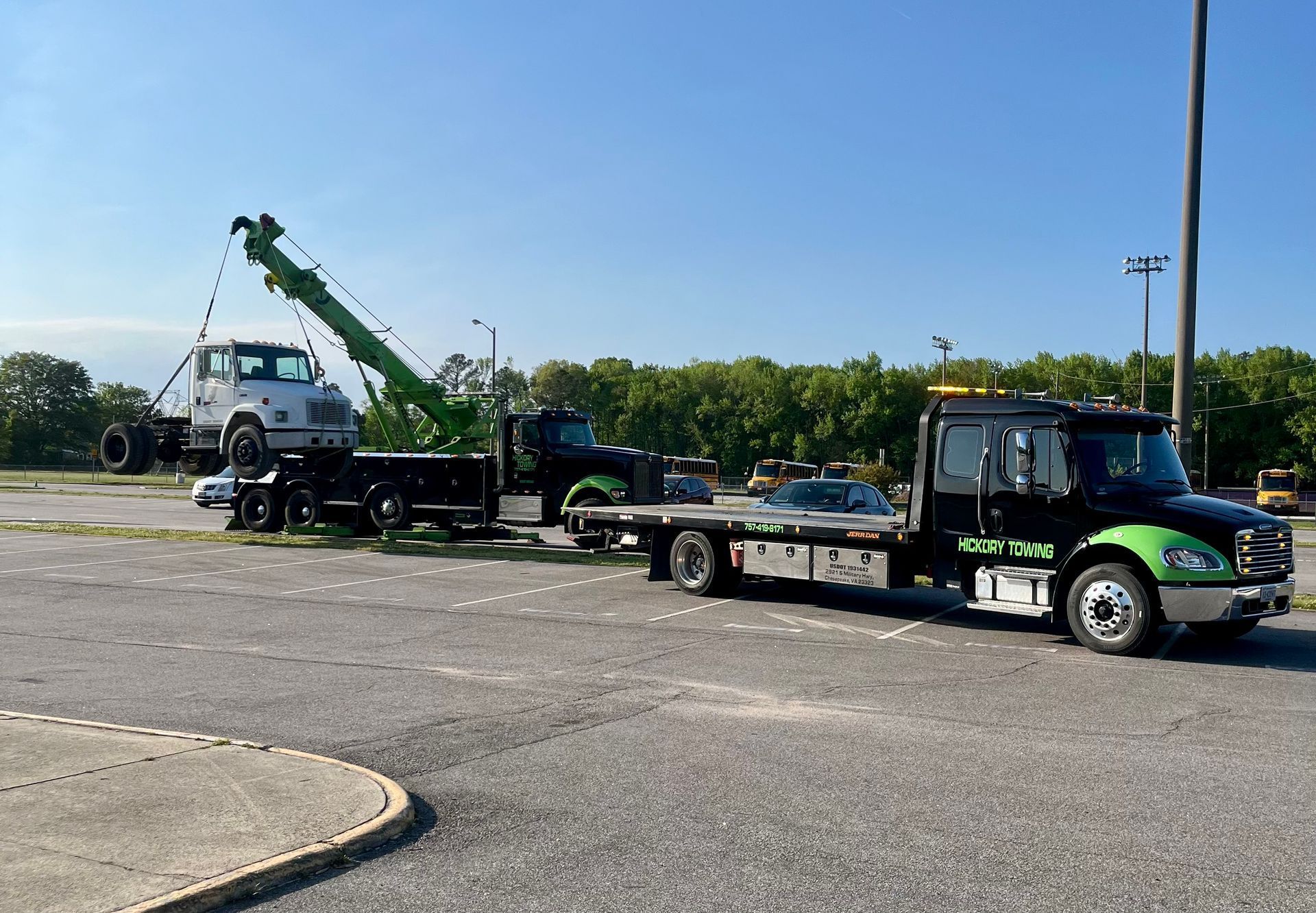 A tow truck is towing a car in a parking lot.