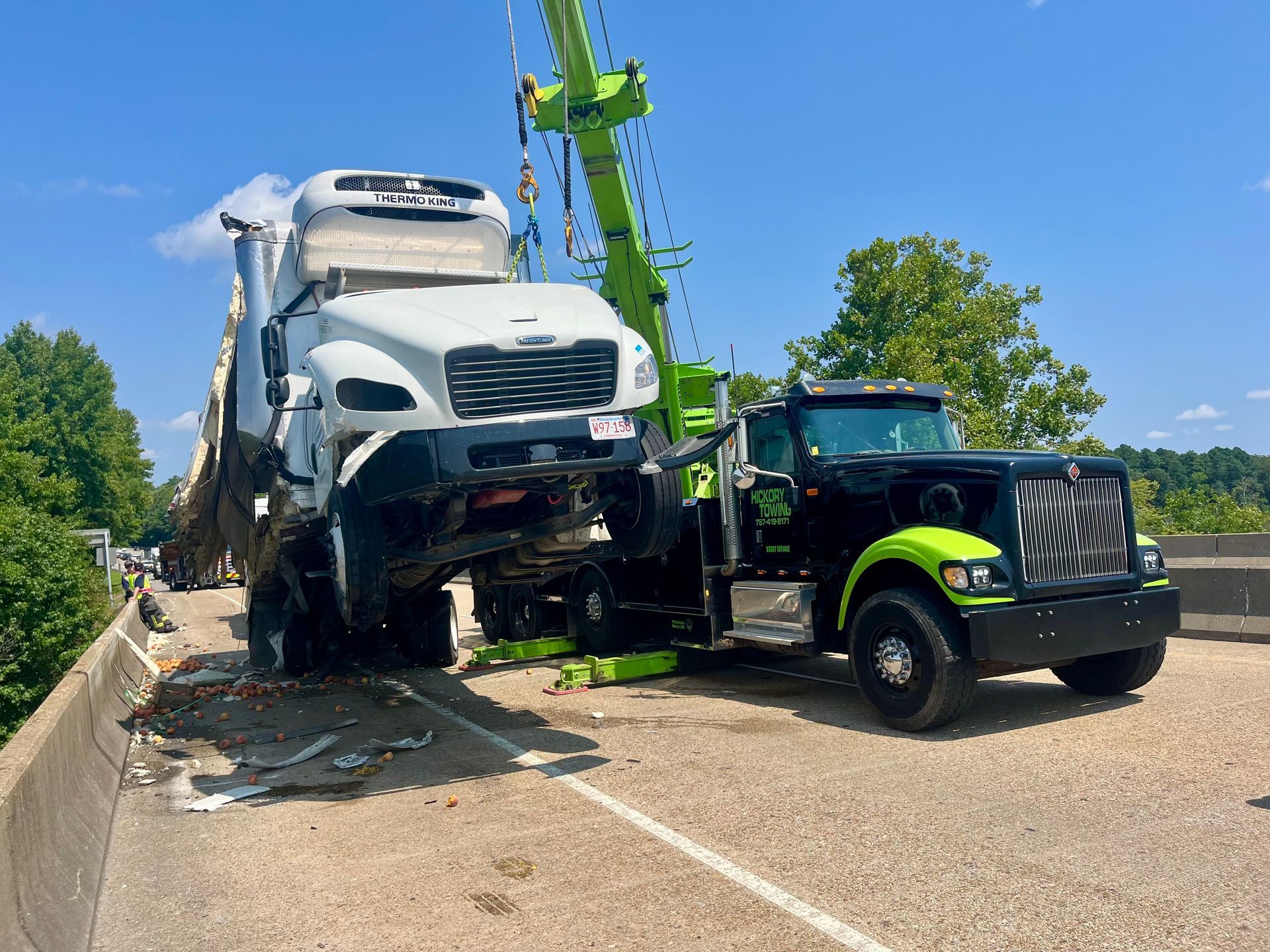 A white truck is being towed by a black tow truck on a highway.
