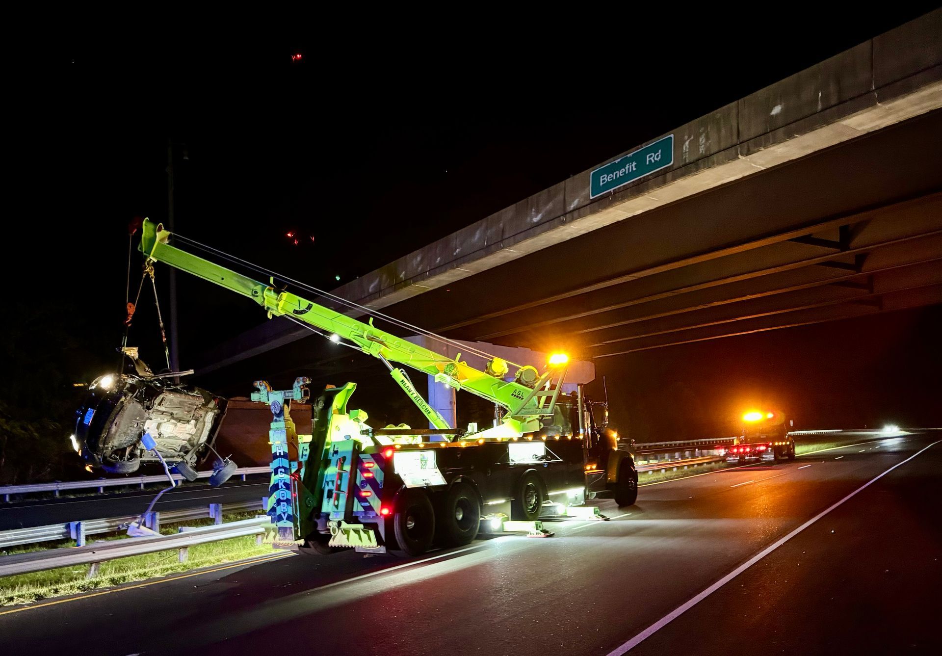 A helicopter is being lifted by a tow truck on a highway at night.
