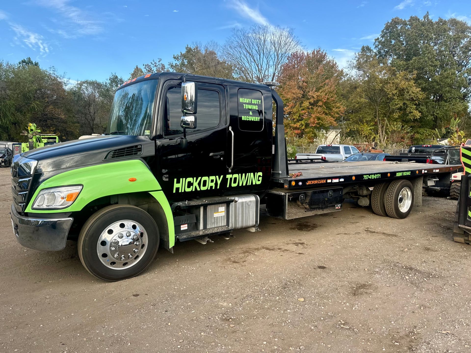 A black and green tow truck is parked in a parking lot.