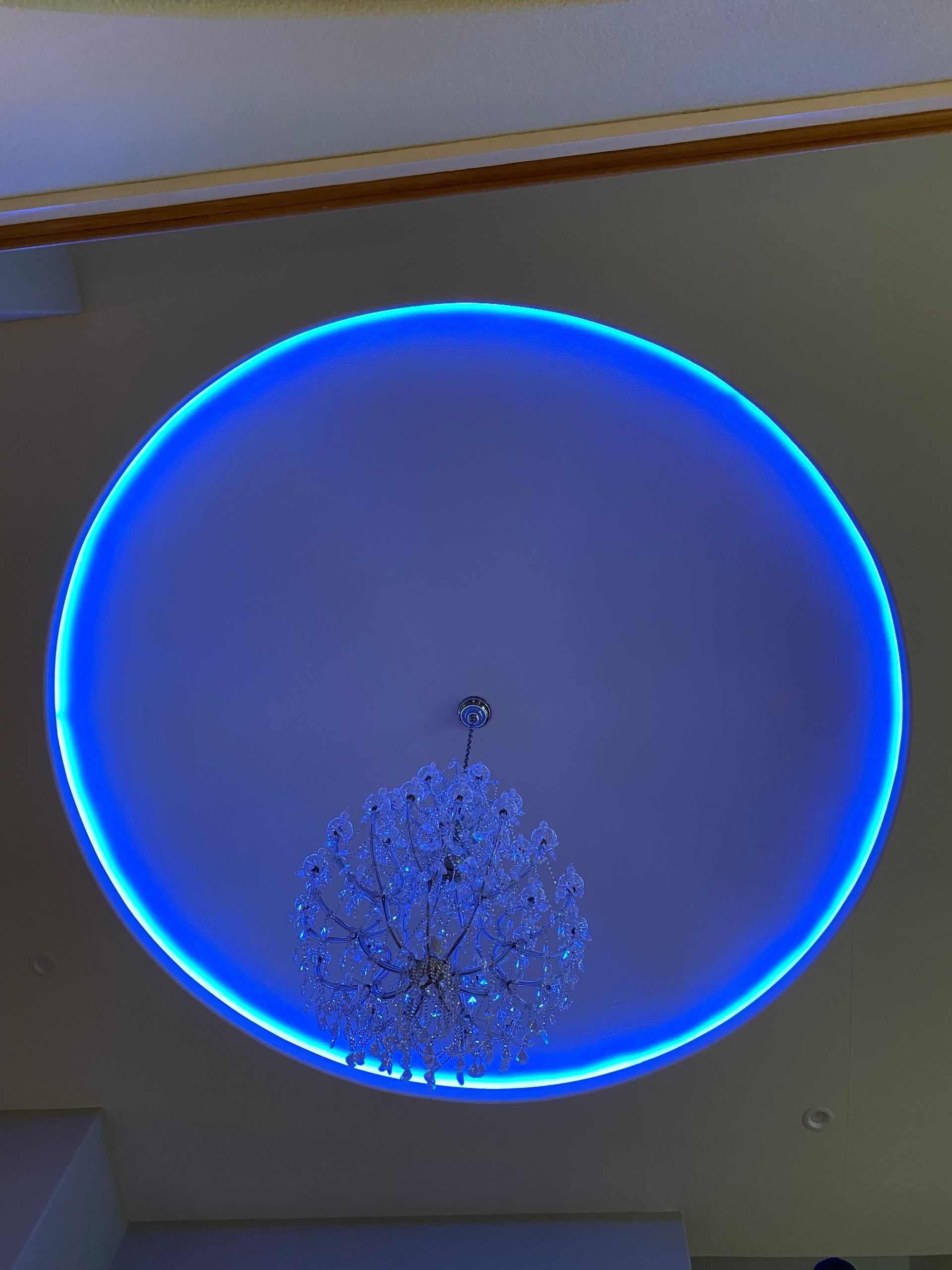 A chandelier is hanging from the ceiling of a room with a blue light around it.