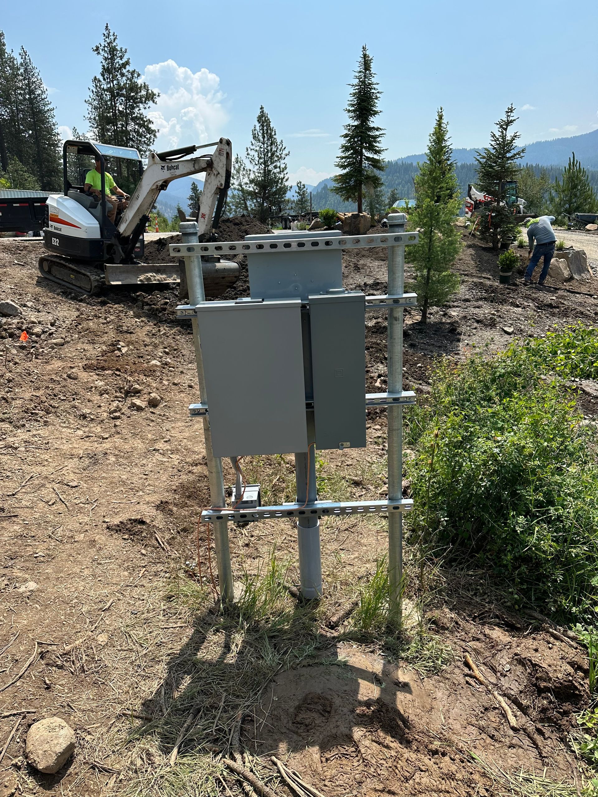 A box is sitting in the middle of a dirt field with a bulldozer in the background.