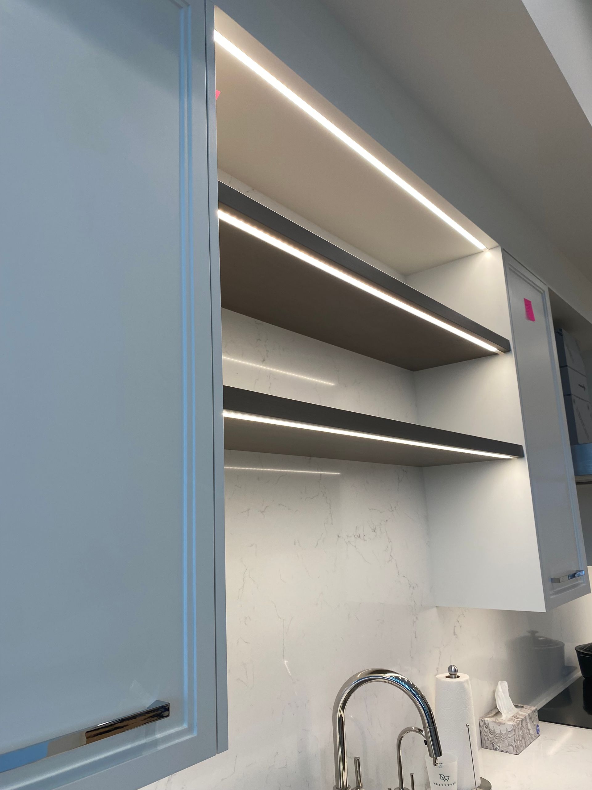 A kitchen with a sink , faucet , and shelves.