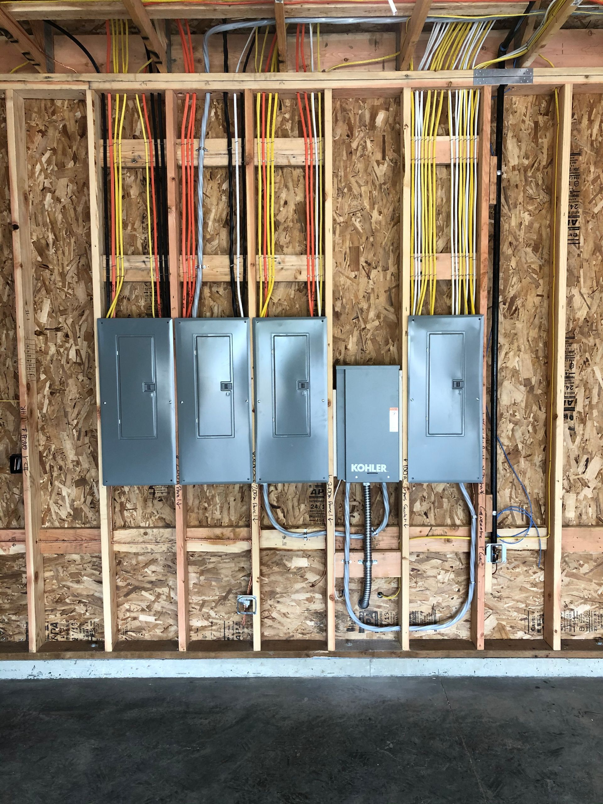 A wall with electrical panels and wires hanging from it.