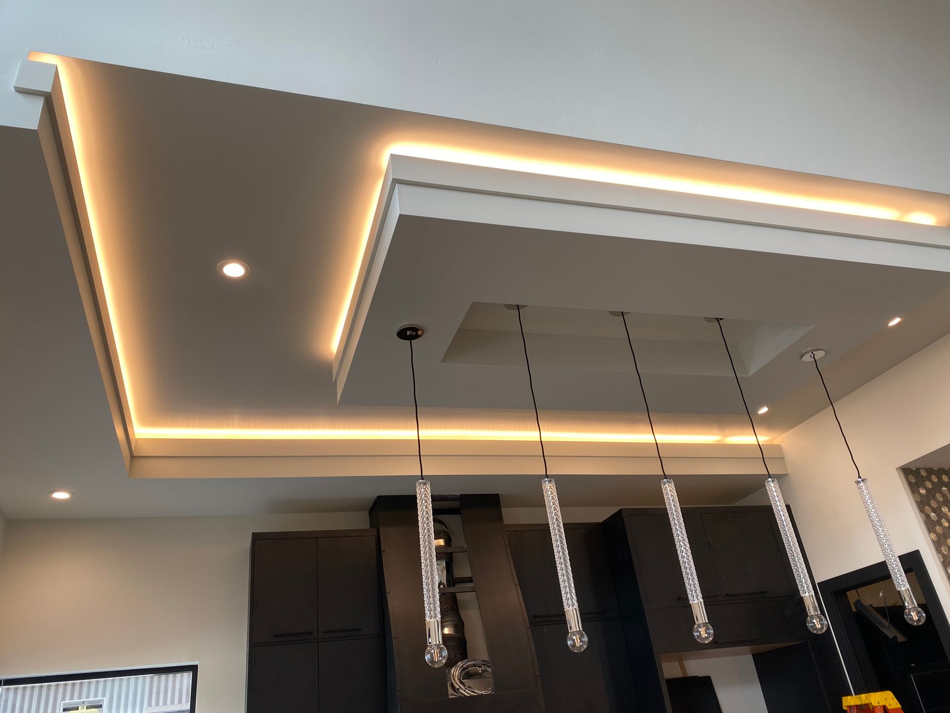 A kitchen with a ceiling that has lights hanging from it