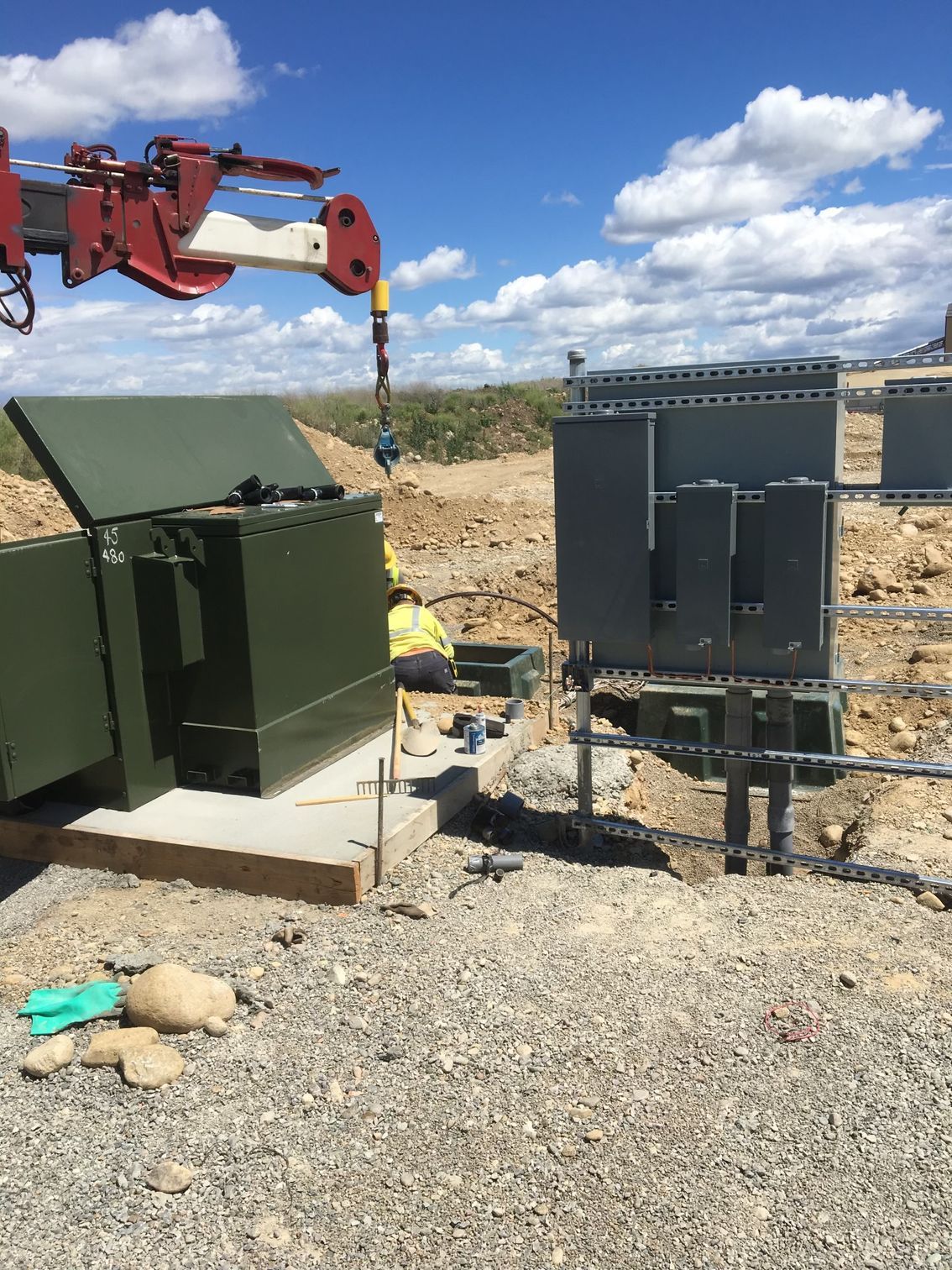 A crane is lifting a green box in the dirt.