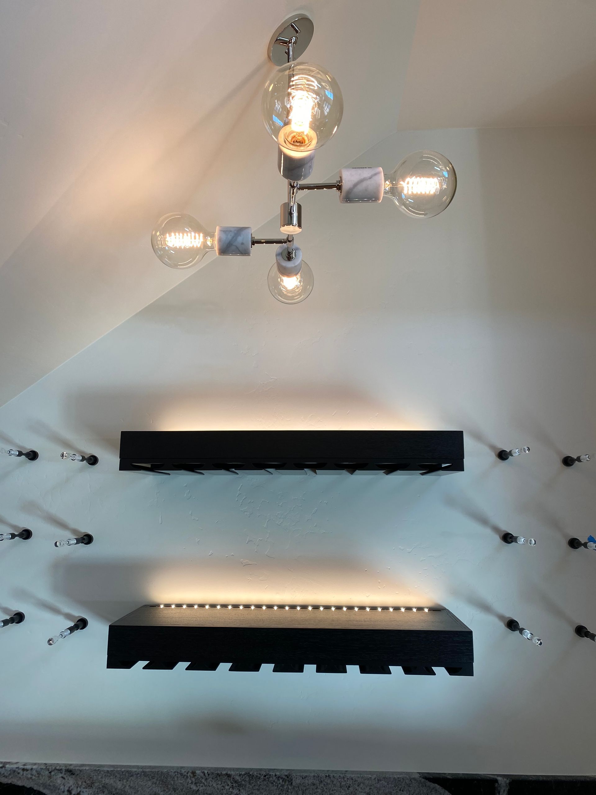 A light fixture is hanging from the ceiling above two shelves.