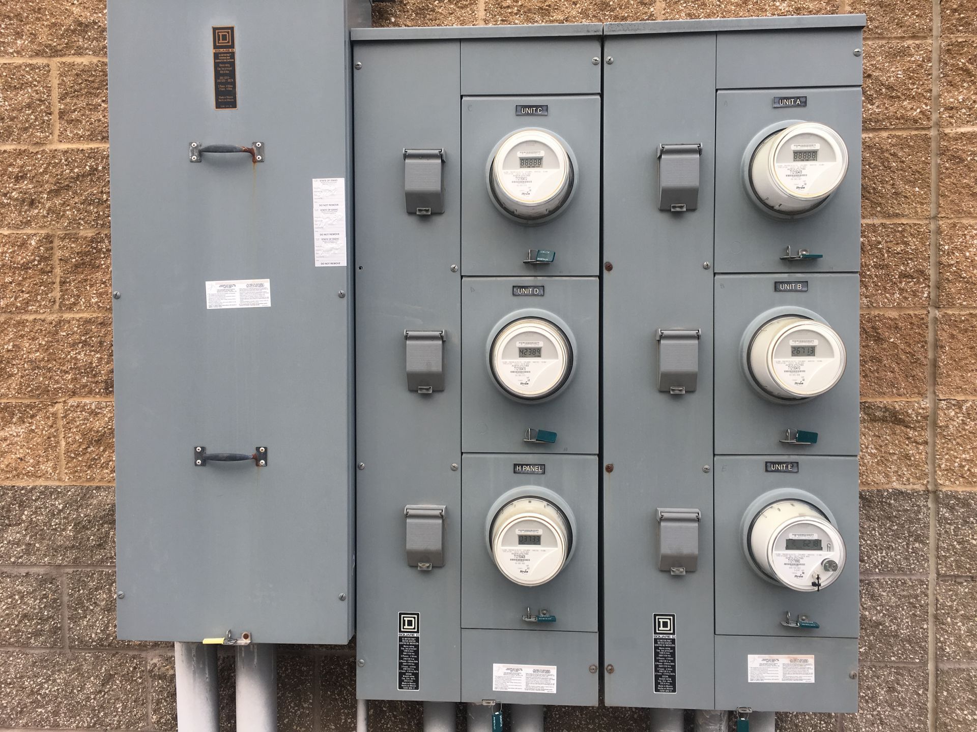 A row of electrical meters on a brick wall.
