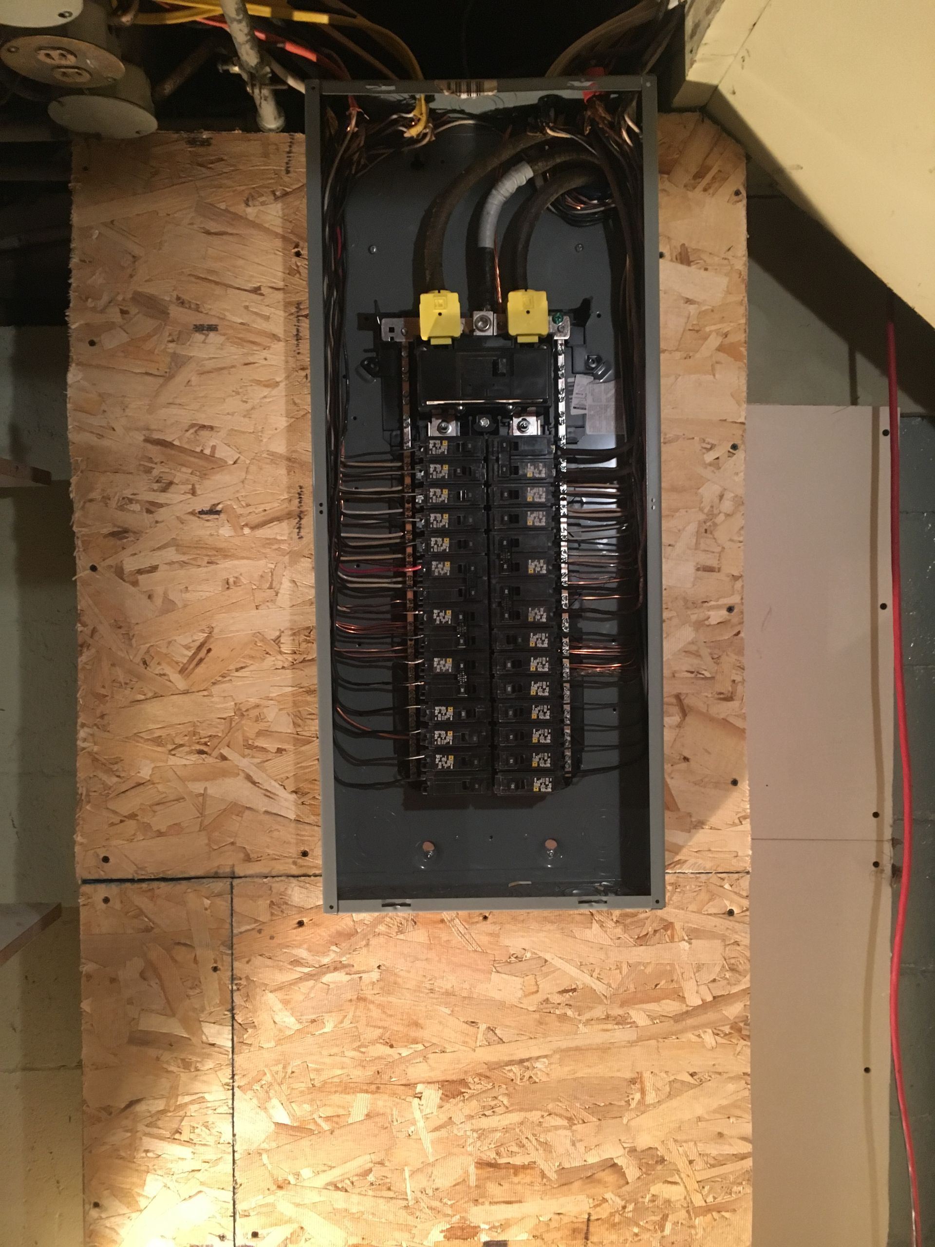 A electrical box is sitting on a wooden wall.