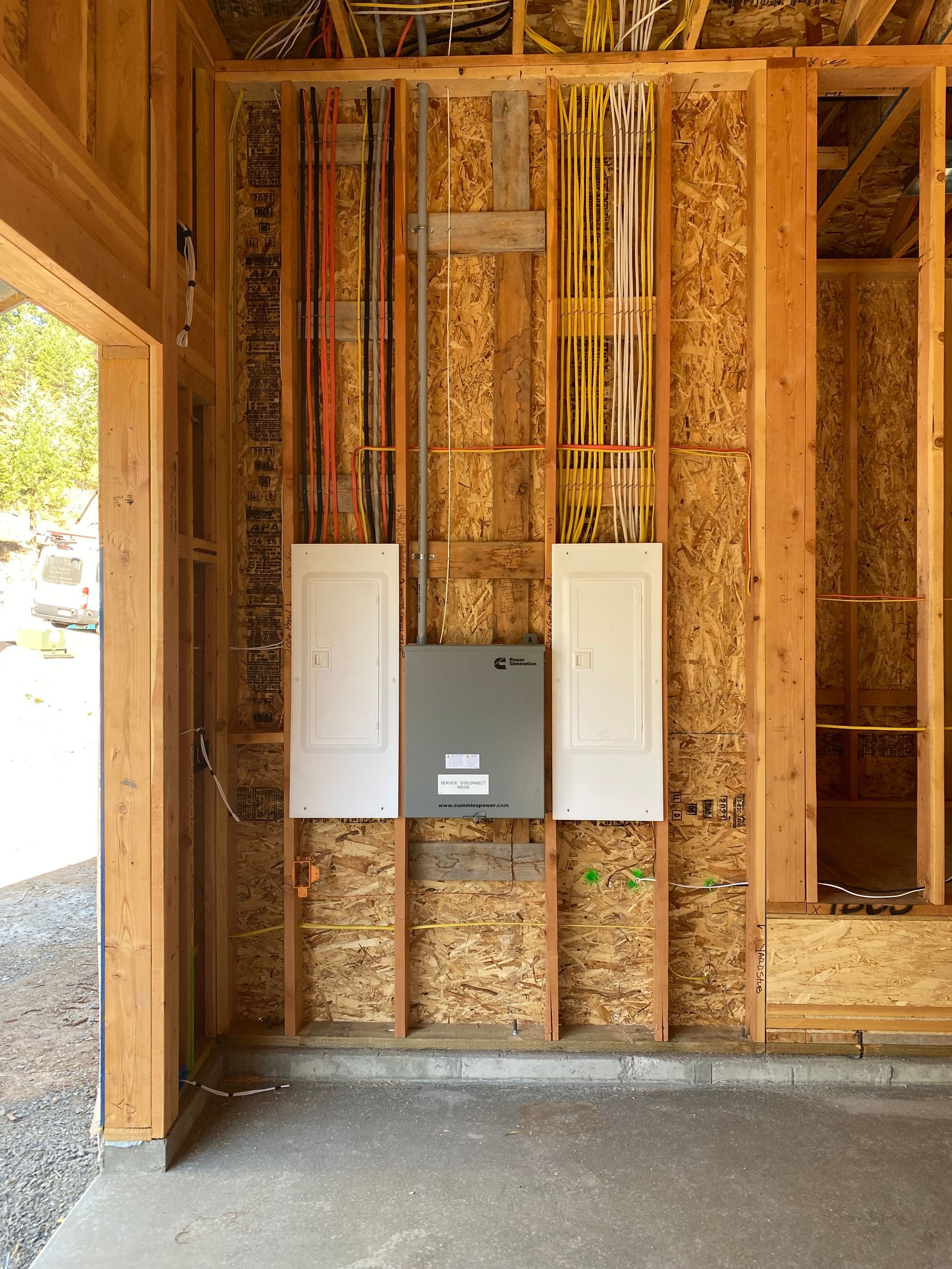 A wooden wall with electrical panels and wires hanging from it
