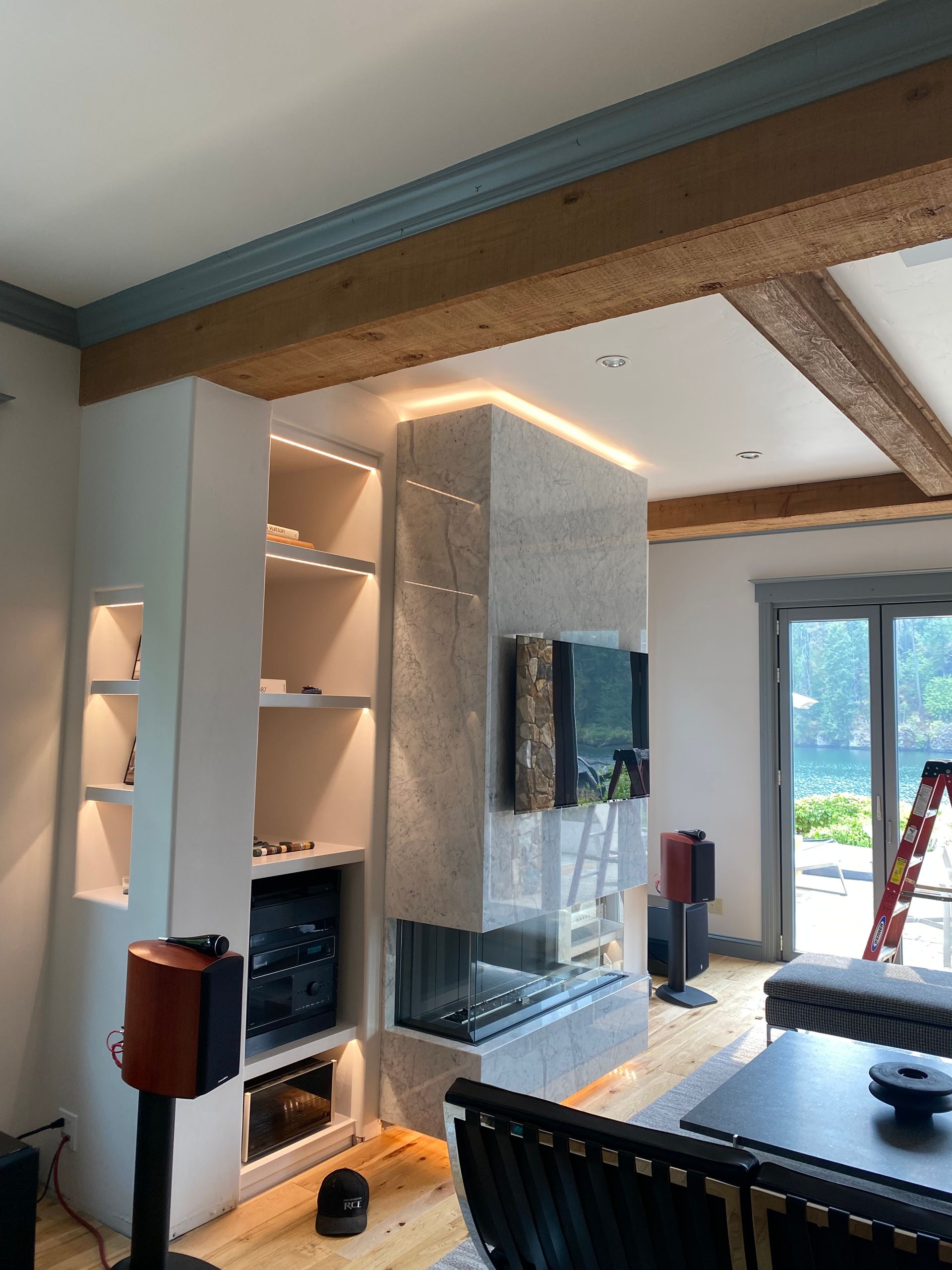 A living room with a fireplace , television , speakers and a ladder.