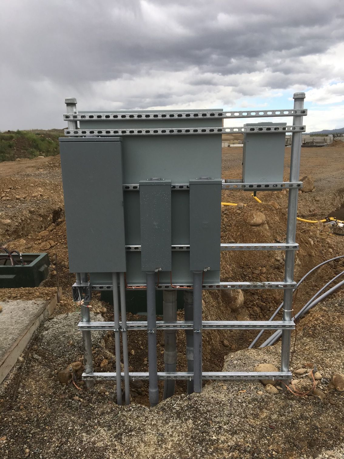 A large electrical box is sitting in the middle of a dirt field.