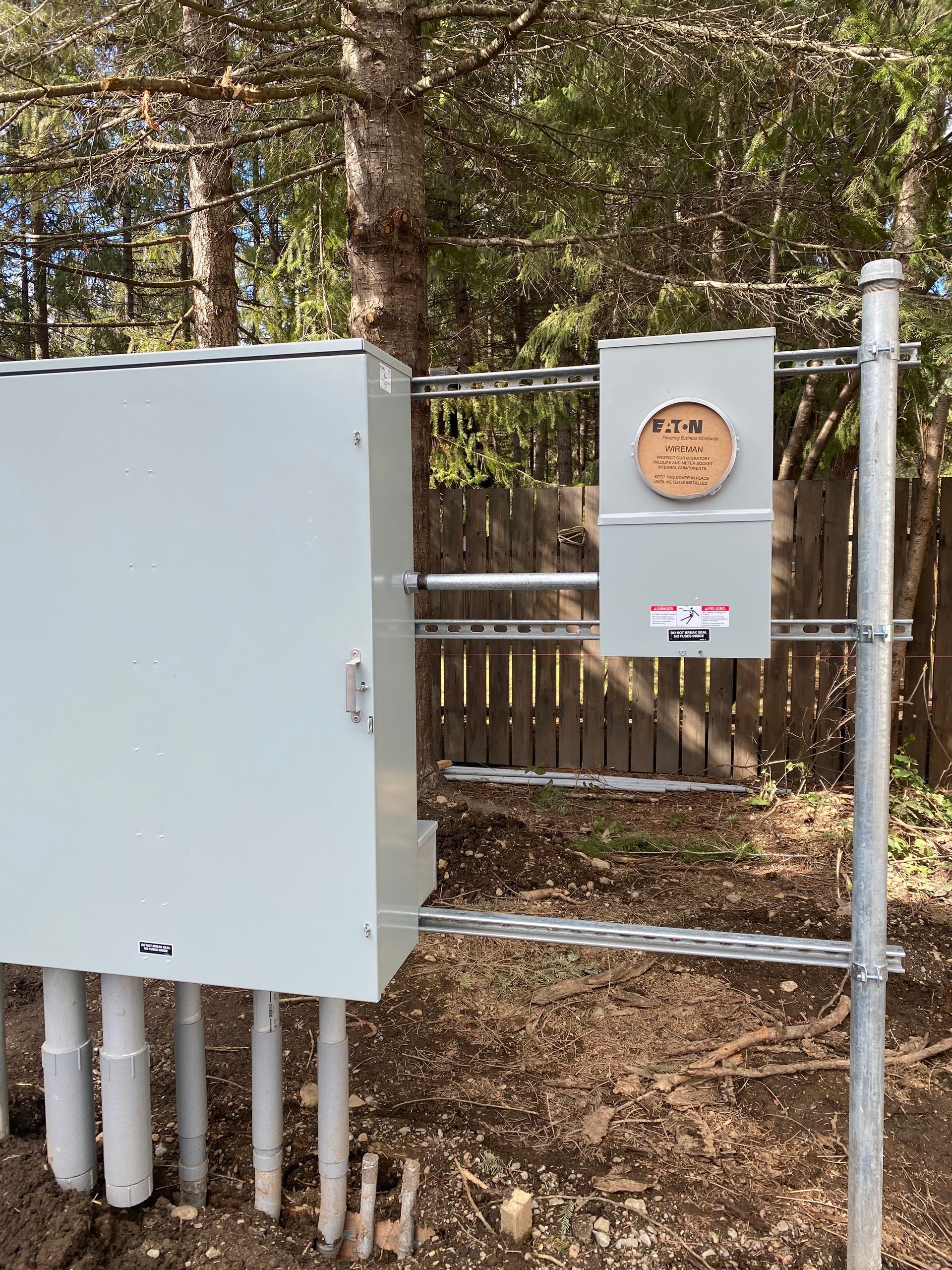 A white box is sitting on top of a metal pole next to a fence.