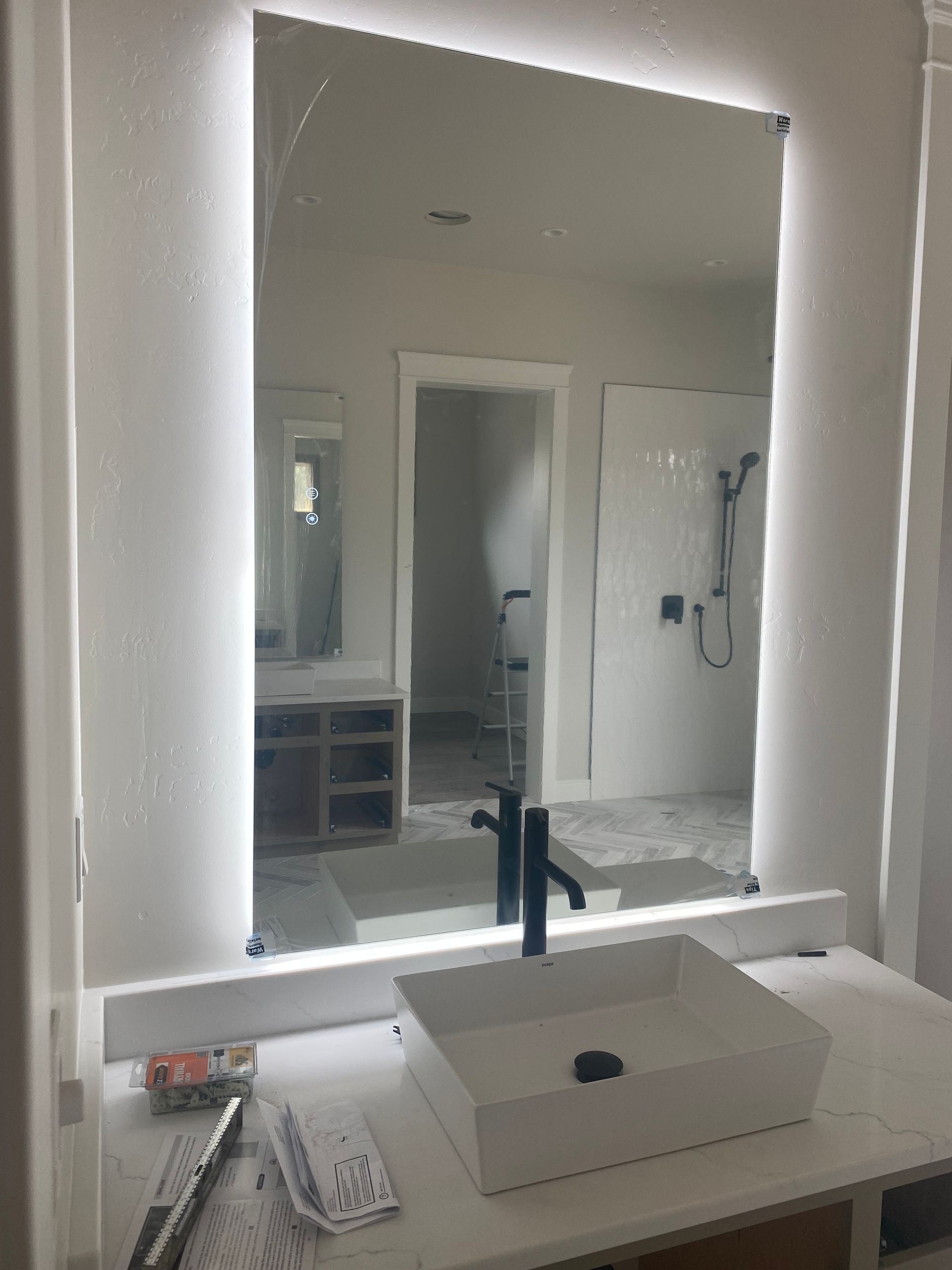 A bathroom with a sink and a mirror with lights on it.
