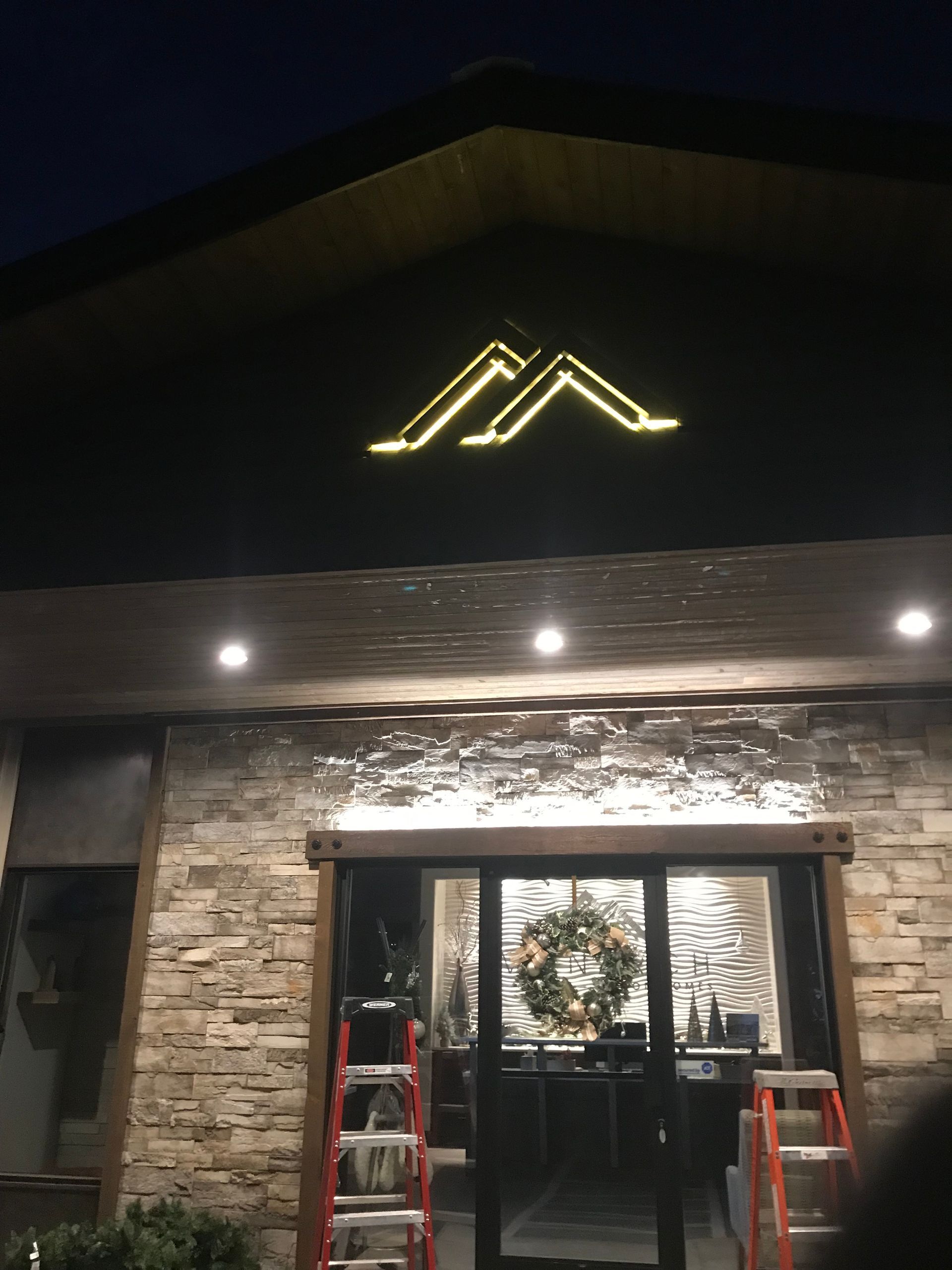 The front of a building with a wreath on the door and a ladder in front of it.