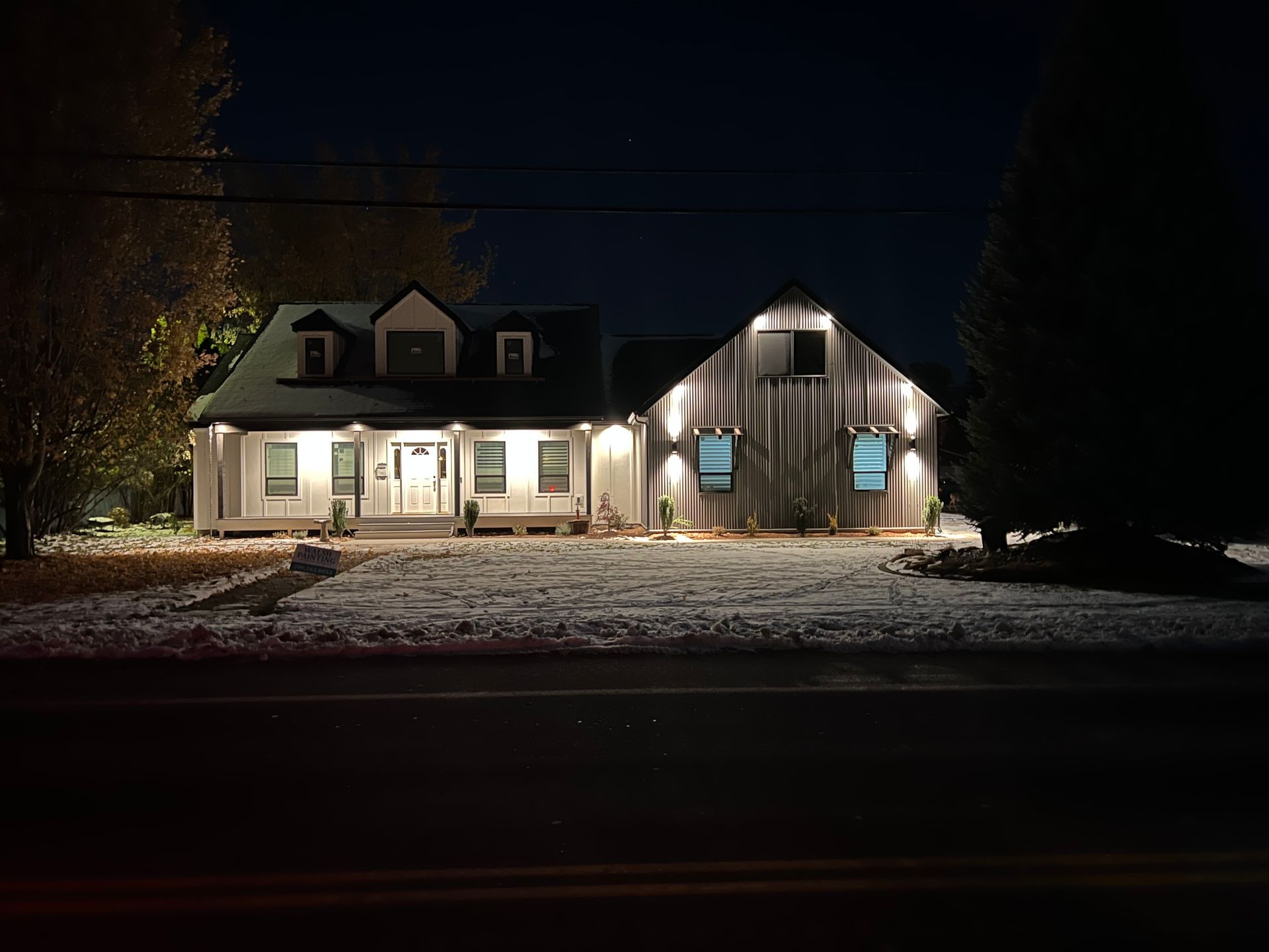 A house is lit up at night with snow on the ground.