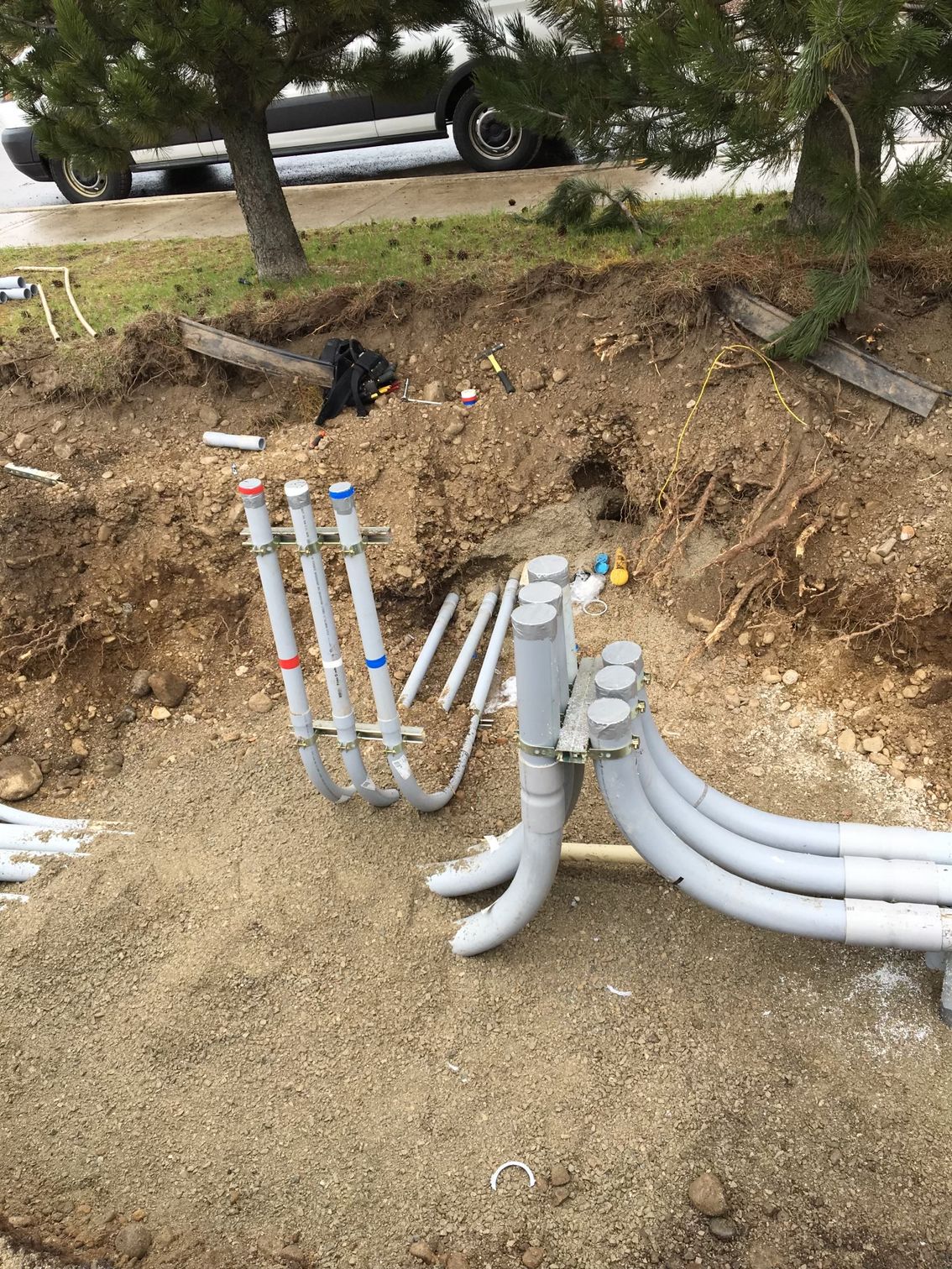 A bunch of pipes are laying in the dirt on the ground.