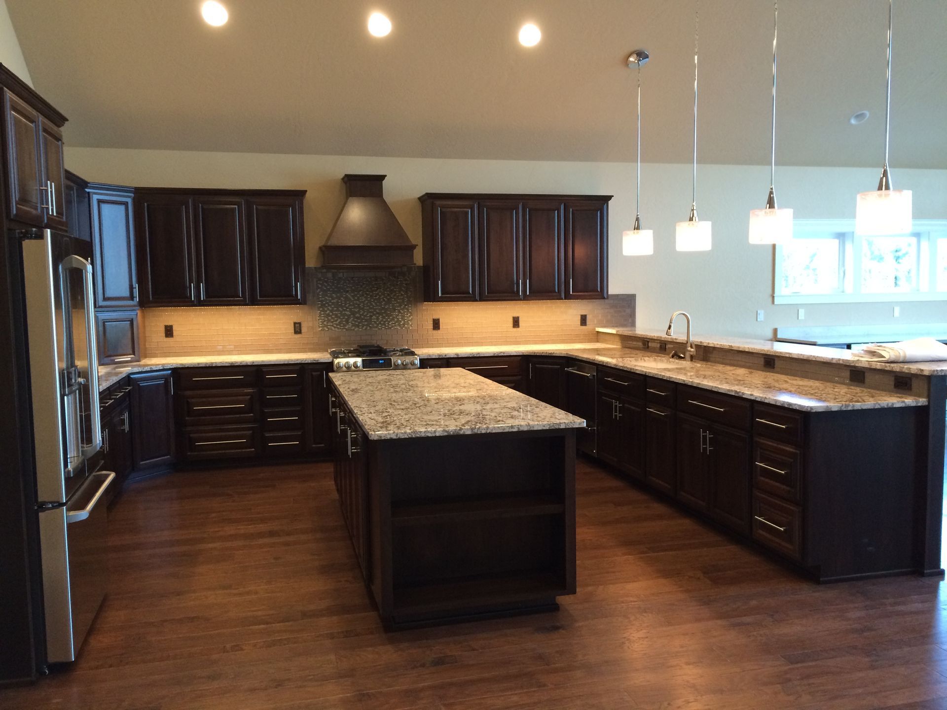 A kitchen with dark cabinets and granite counter tops