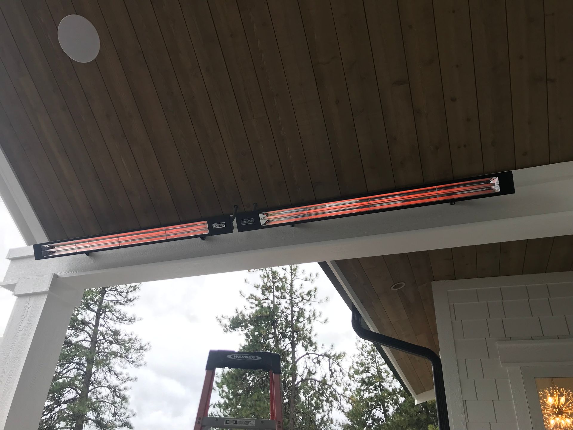 A ladder is hanging from the ceiling of a porch.