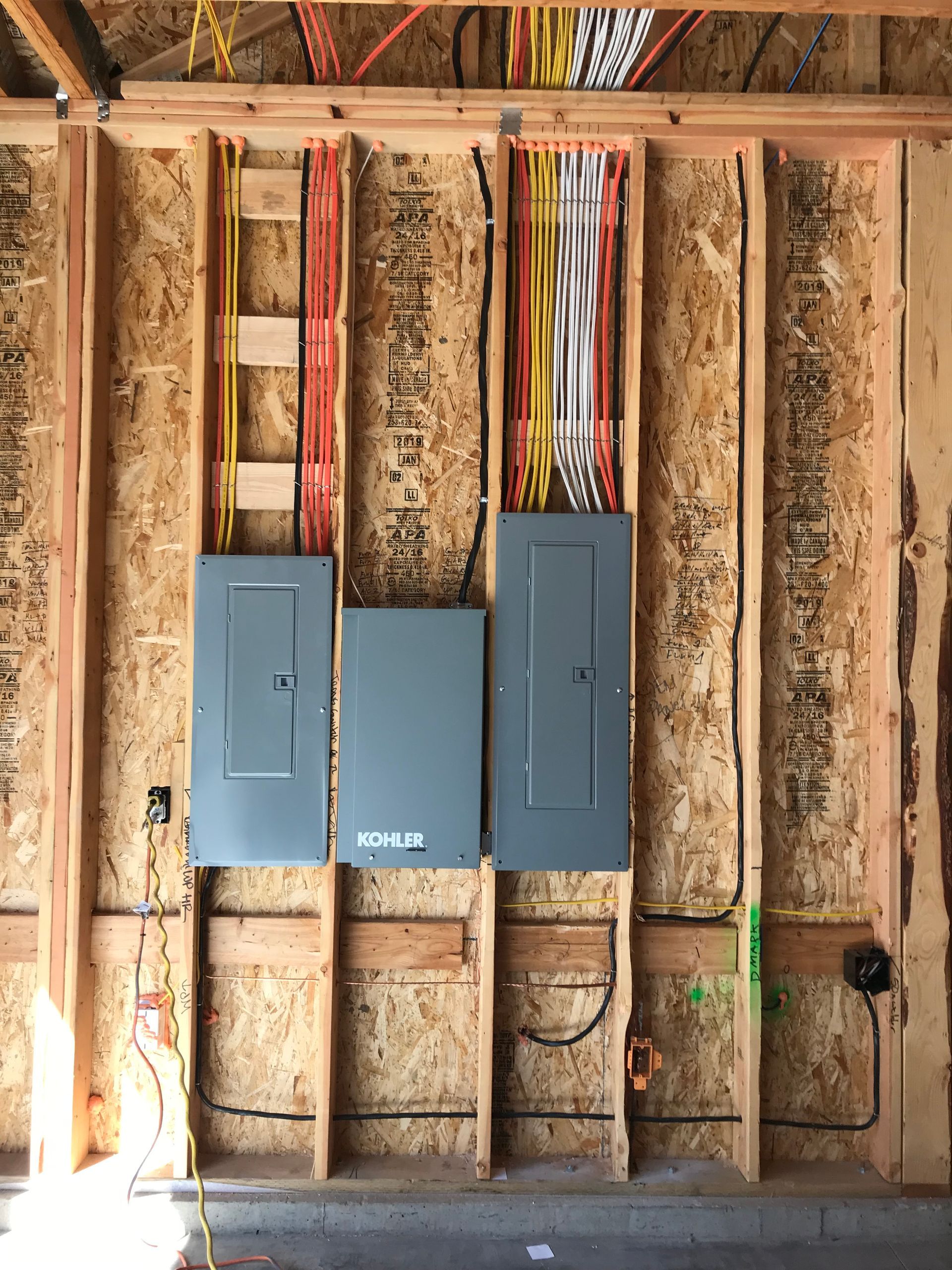 A wooden wall with electrical panels and wires hanging from it.