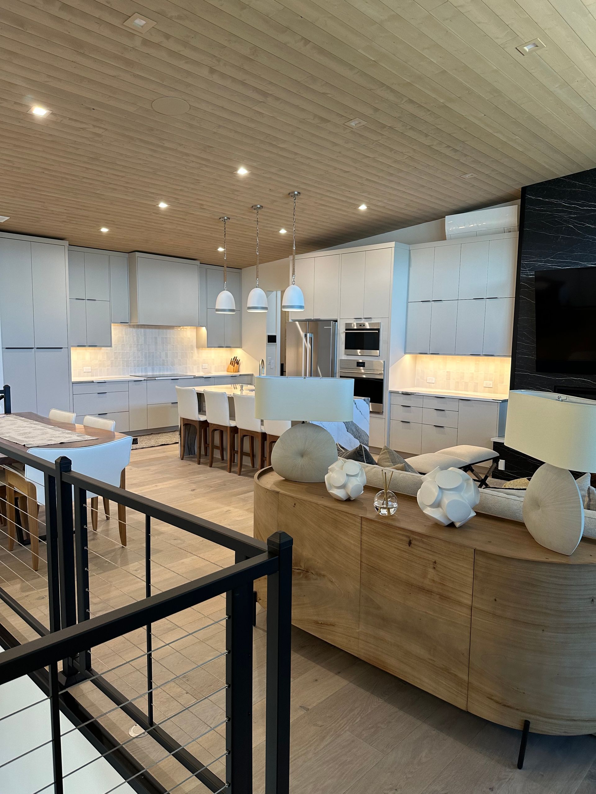 A living room with a wooden table and a black railing