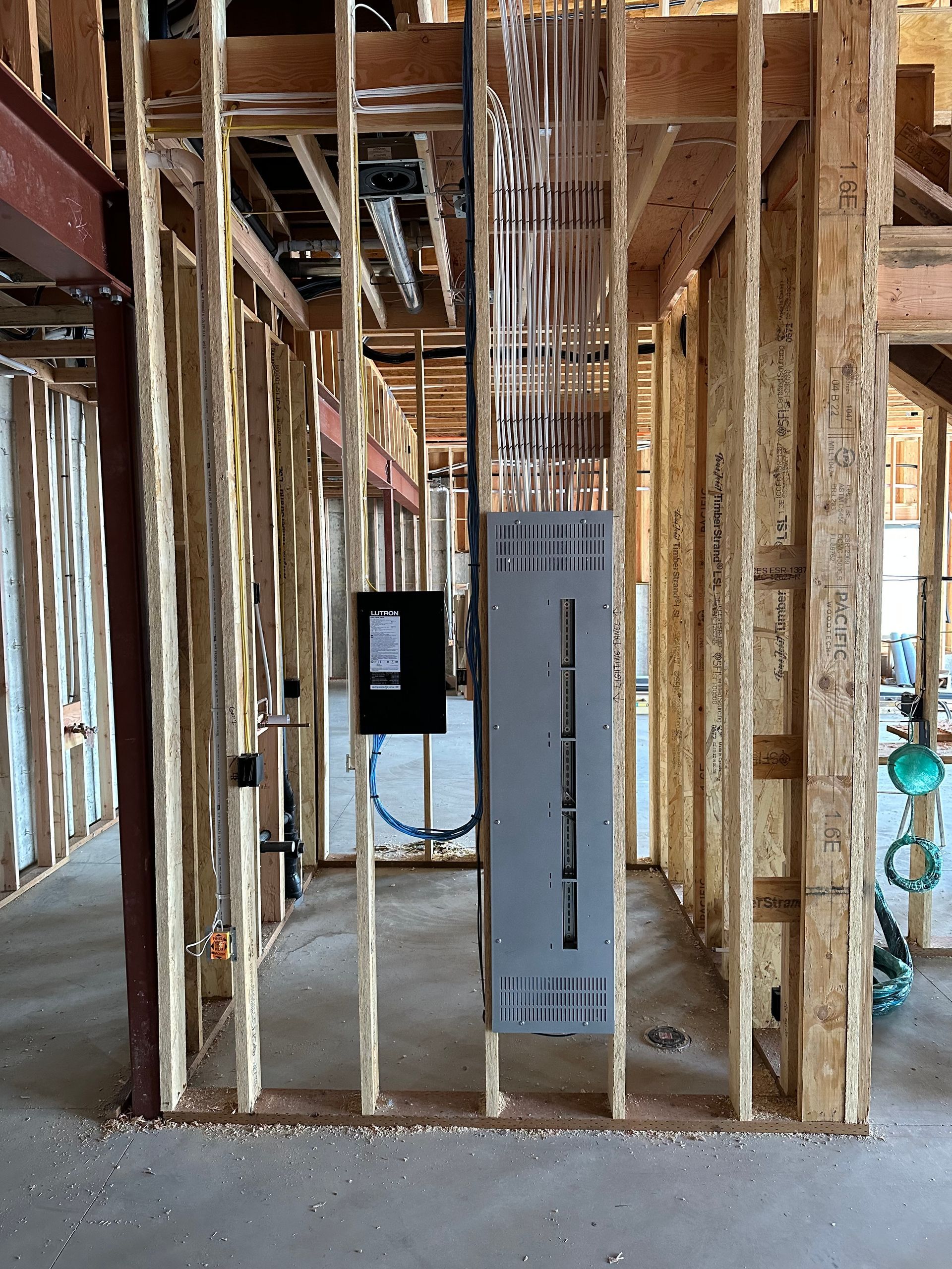 A large electrical box is hanging from the ceiling of a building under construction.