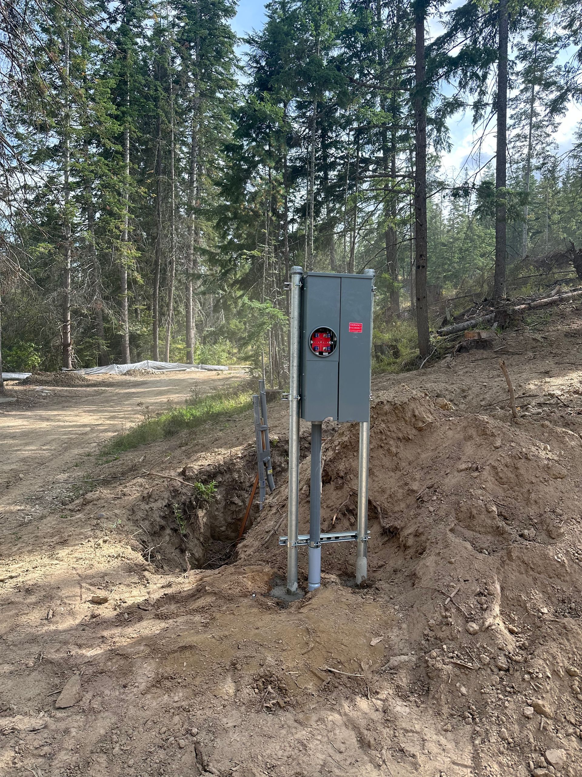 A box is sitting in the middle of a dirt field in the middle of a forest.