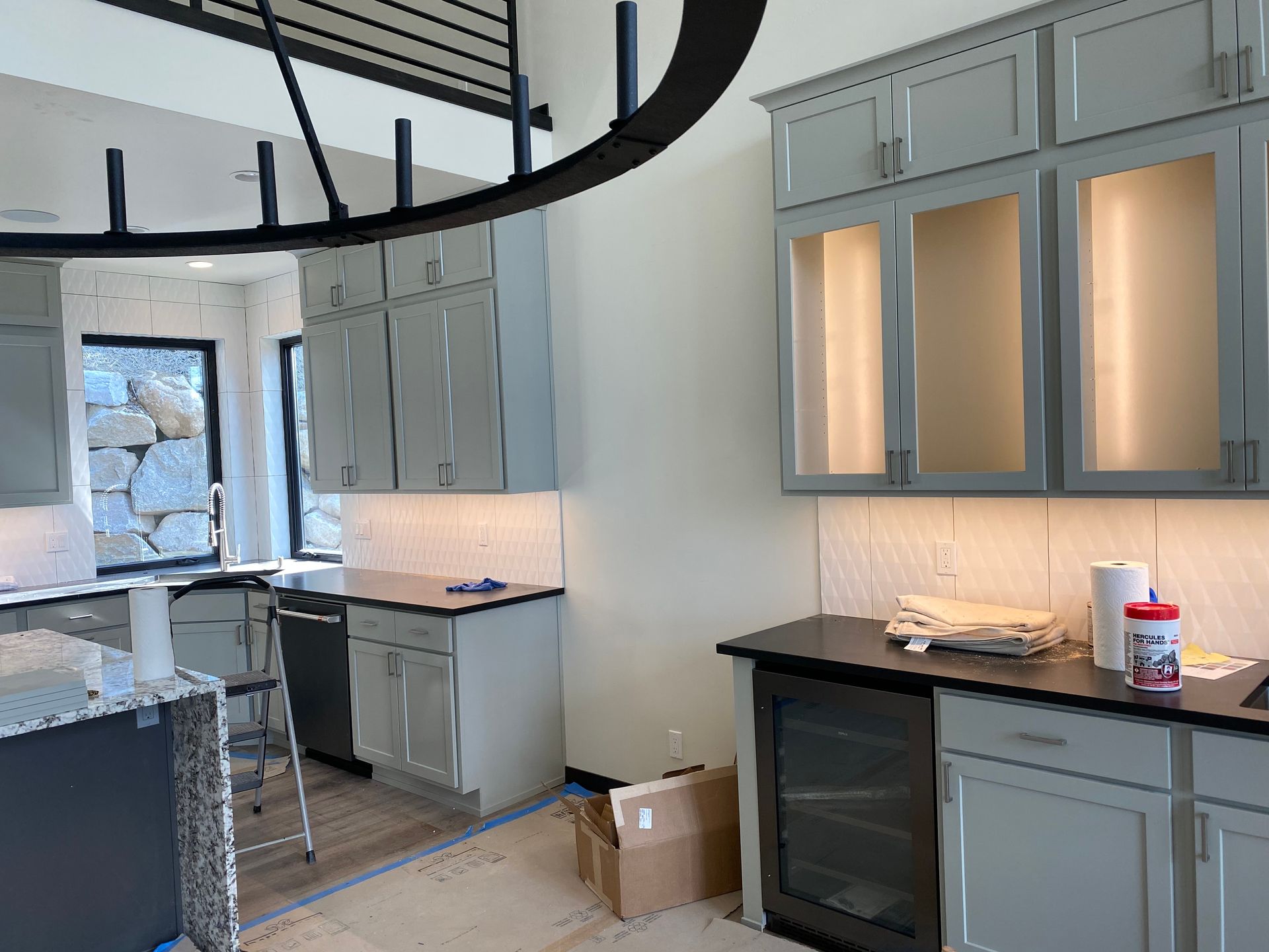 A kitchen with gray cabinets and black counter tops is being remodeled.