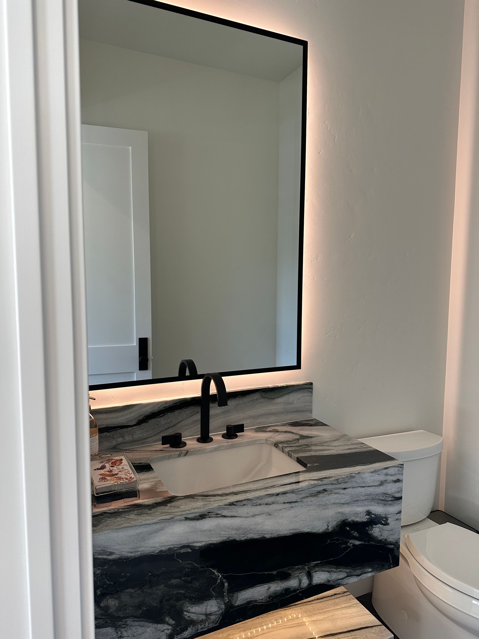 A bathroom with a sink , toilet and mirror.