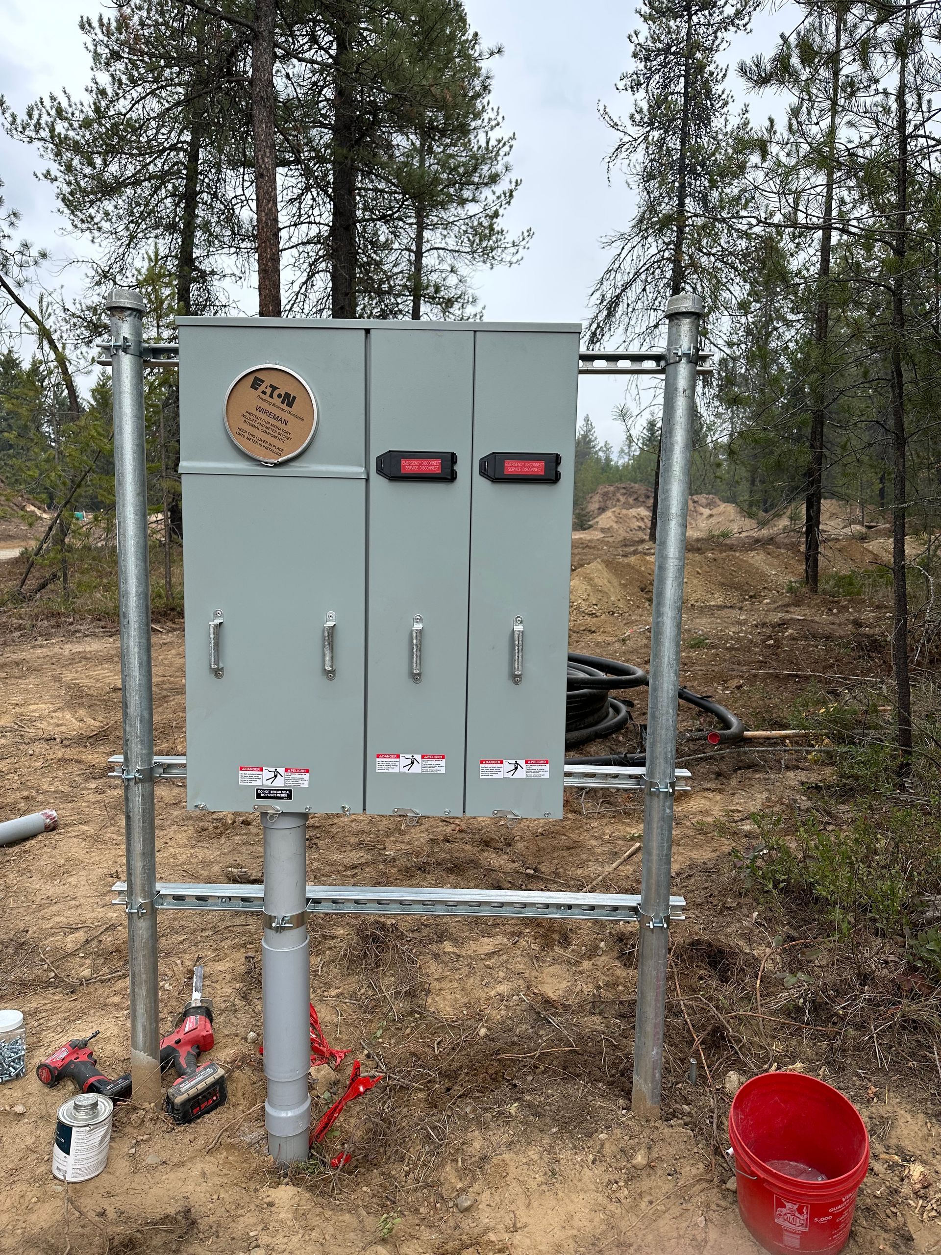 A large electrical box is sitting on top of a metal pole in the middle of a field.