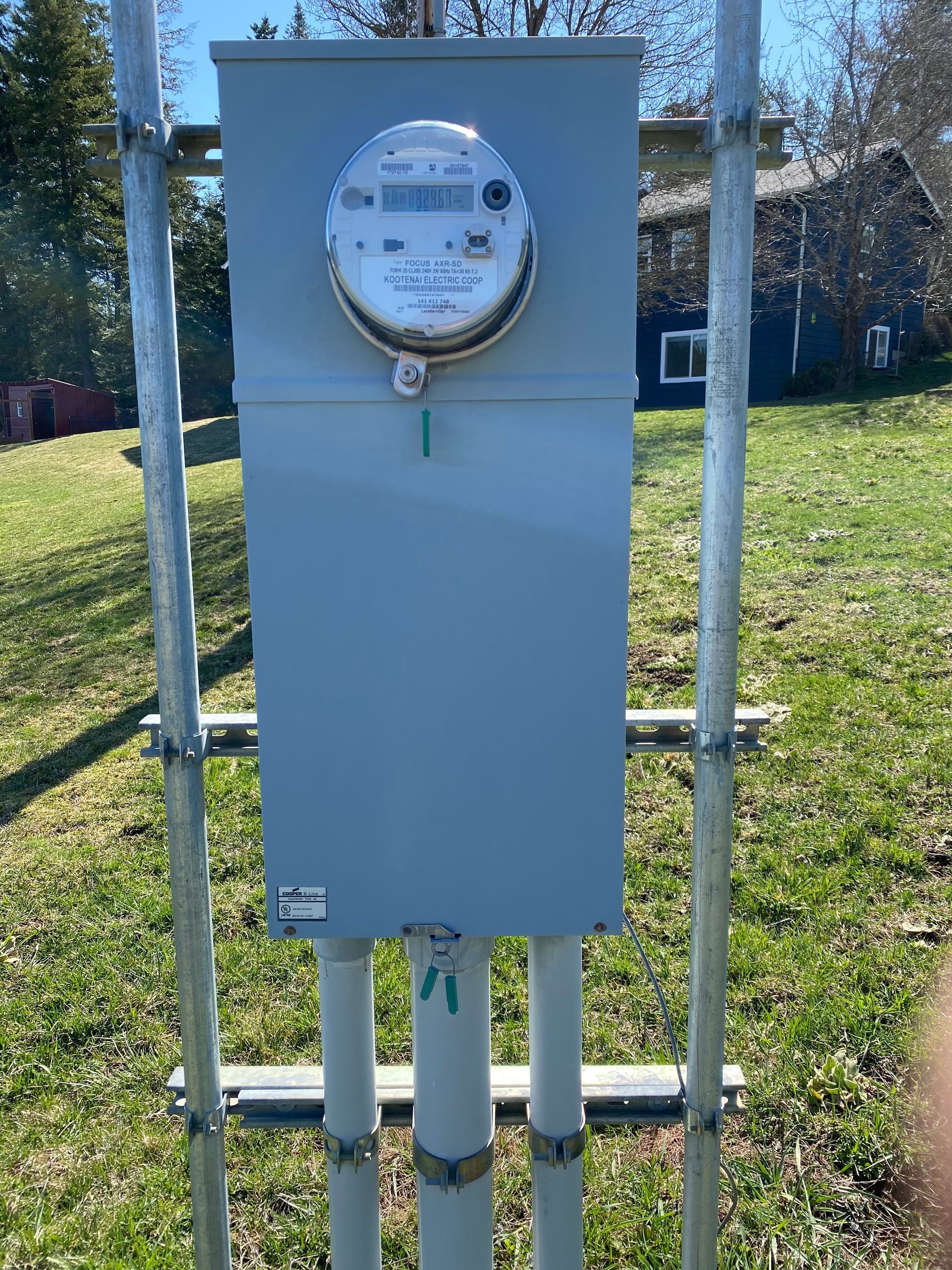 A meter is sitting on top of a pole in a grassy field.
