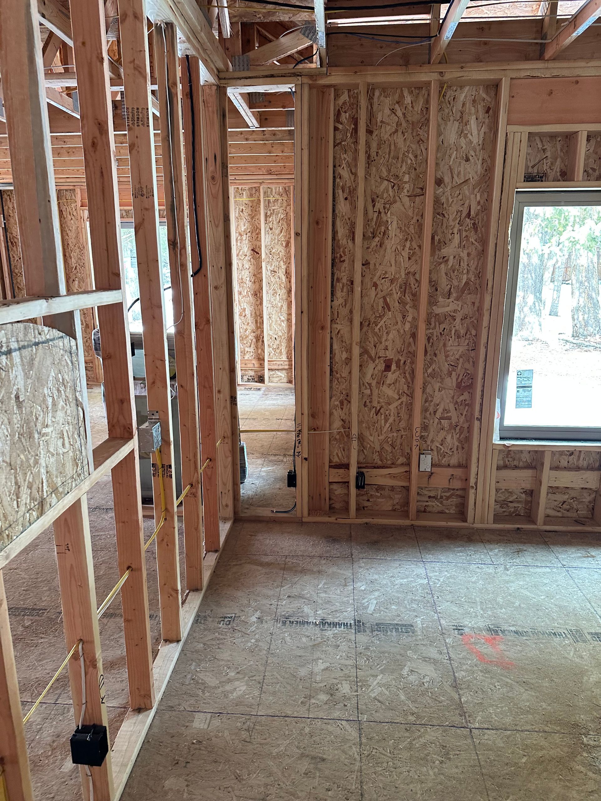 A room in a house under construction with wooden beams and a window.