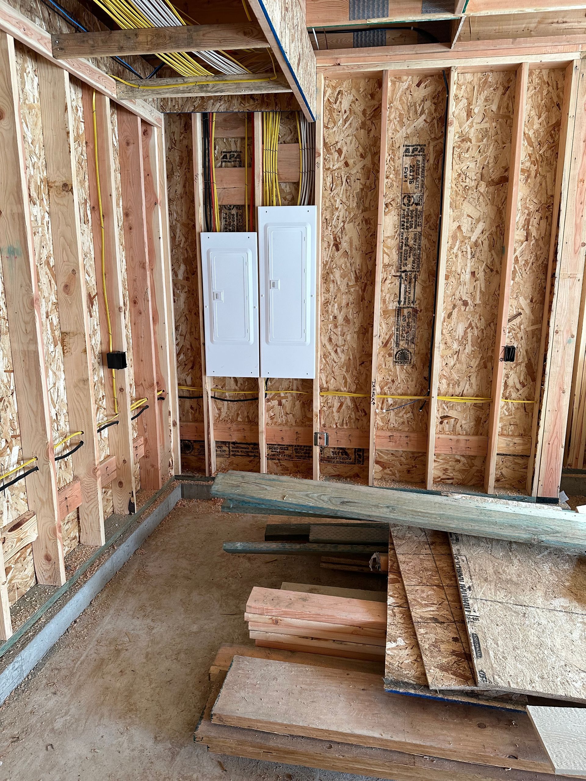 A room in a house under construction with wooden walls and a ladder.