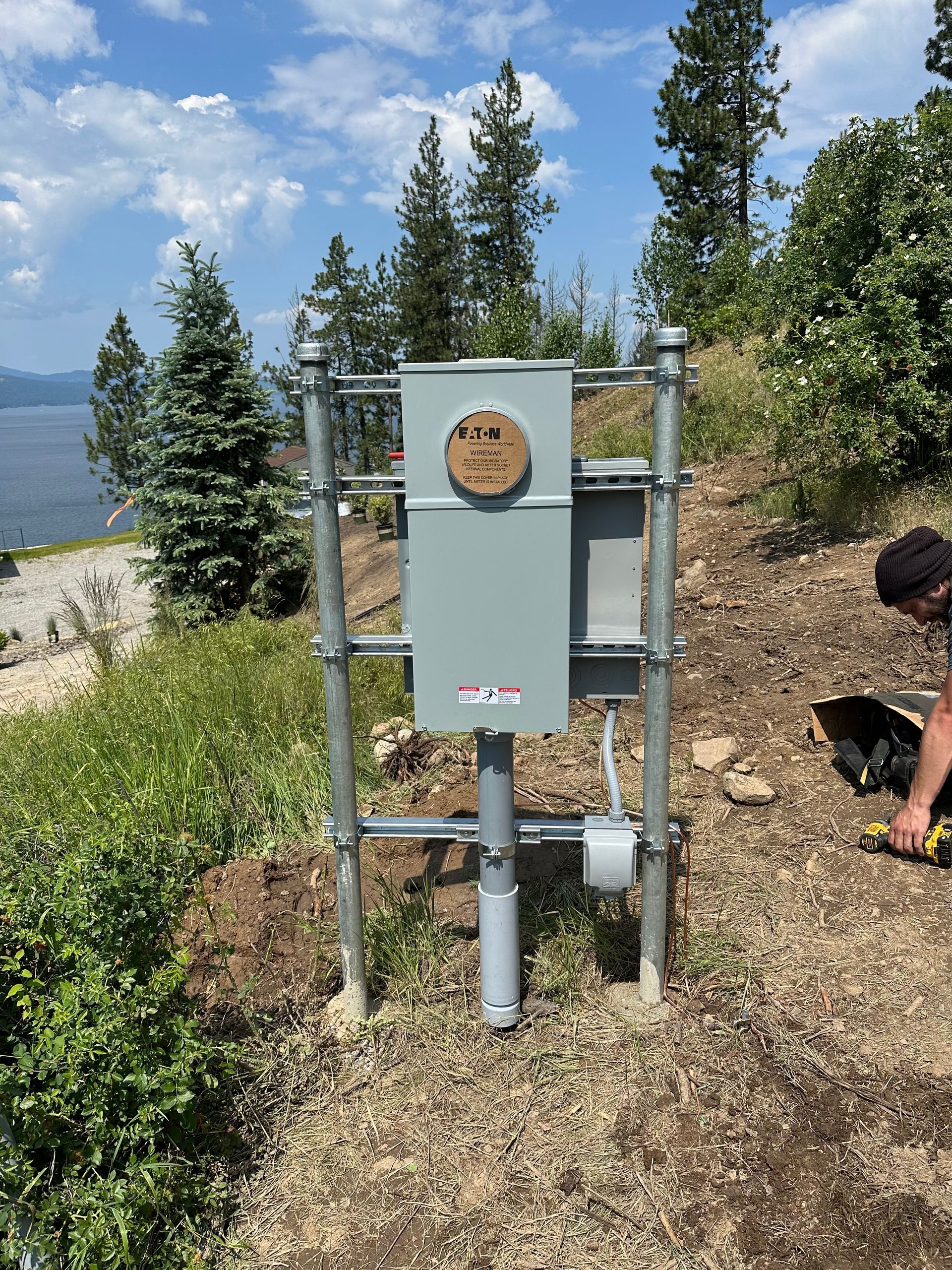 A man is working on a power box on top of a hill.