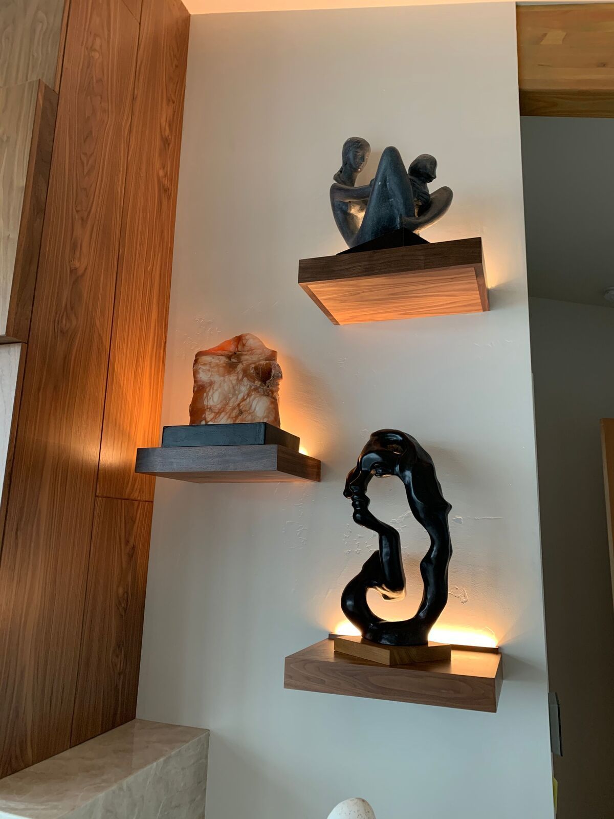 Three shelves with sculptures on them on a wall