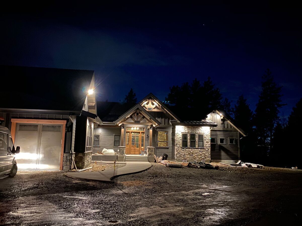 A large house is lit up at night with trees in the background.