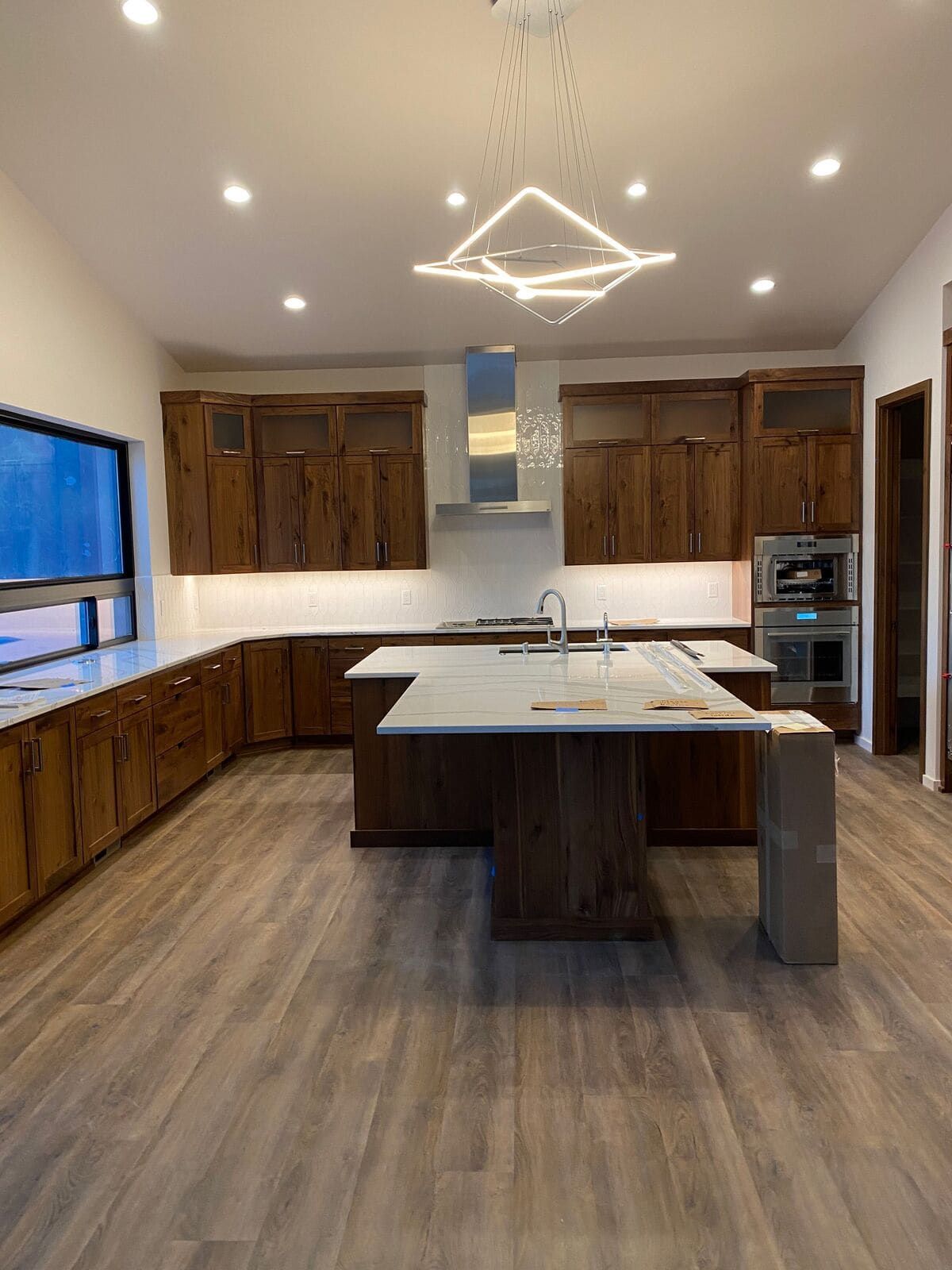 A kitchen with wooden cabinets and a large island in the middle.