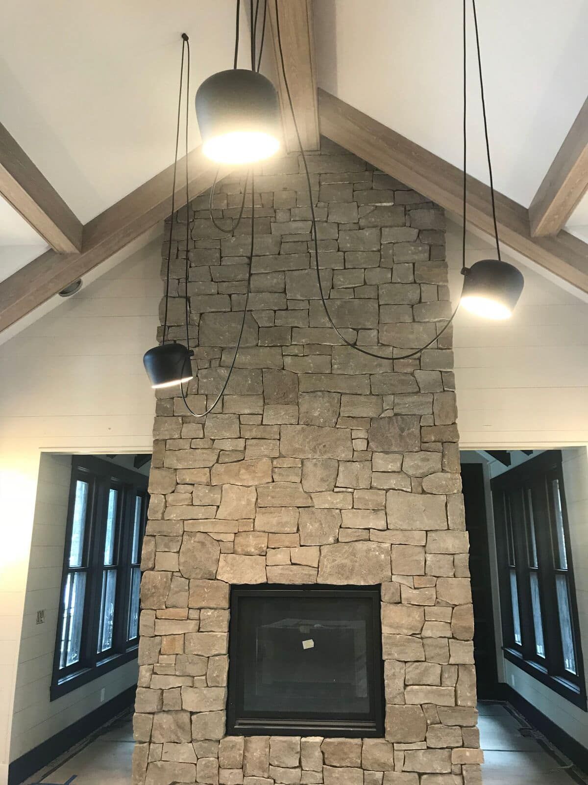 A stone fireplace in a living room with a vaulted ceiling