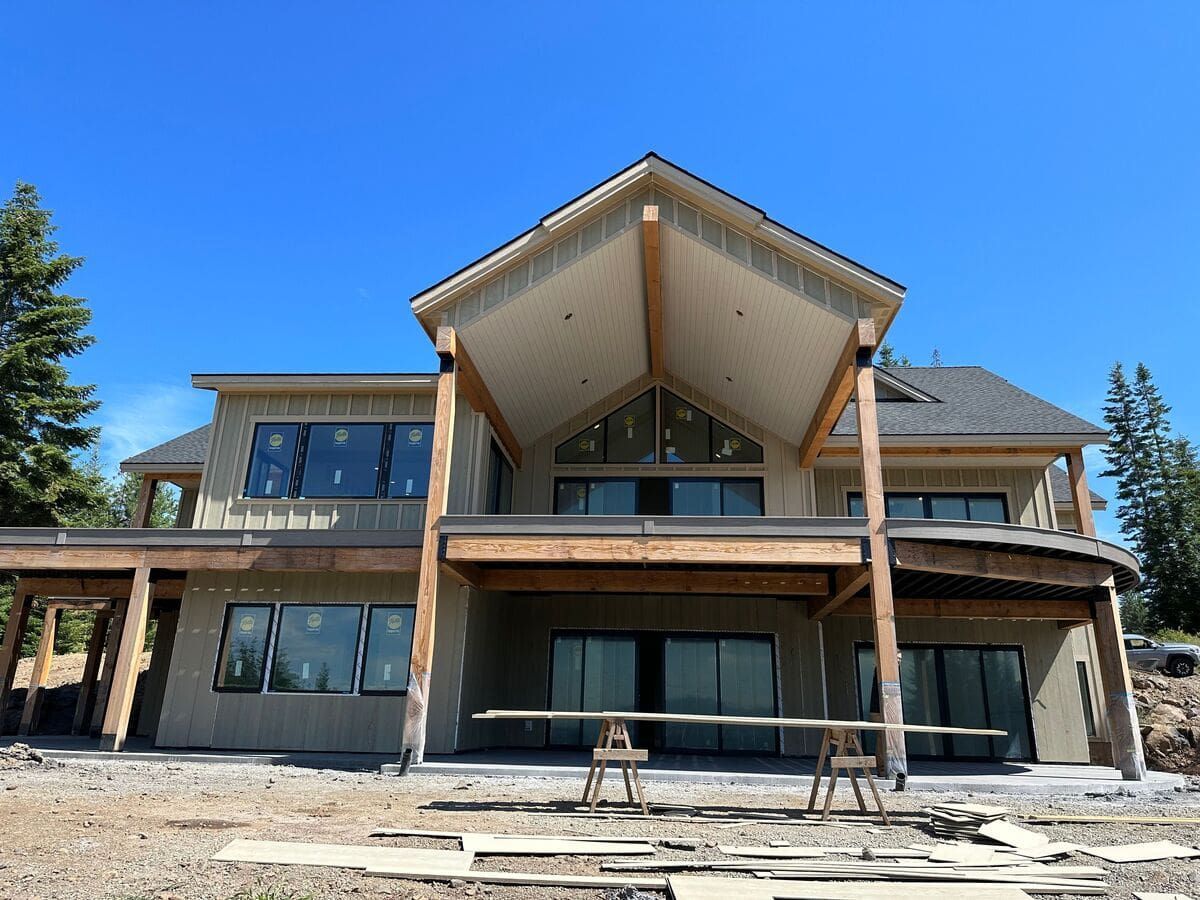 A large house is being built in the middle of a dirt field.
