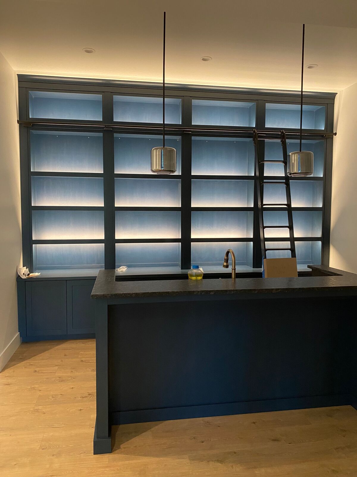 A kitchen with a ladder and lots of shelves