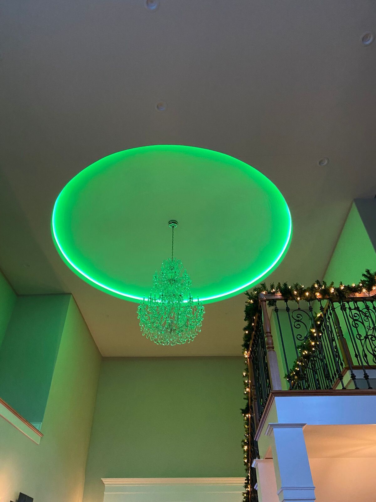 A ceiling with a green light and a chandelier hanging from it.